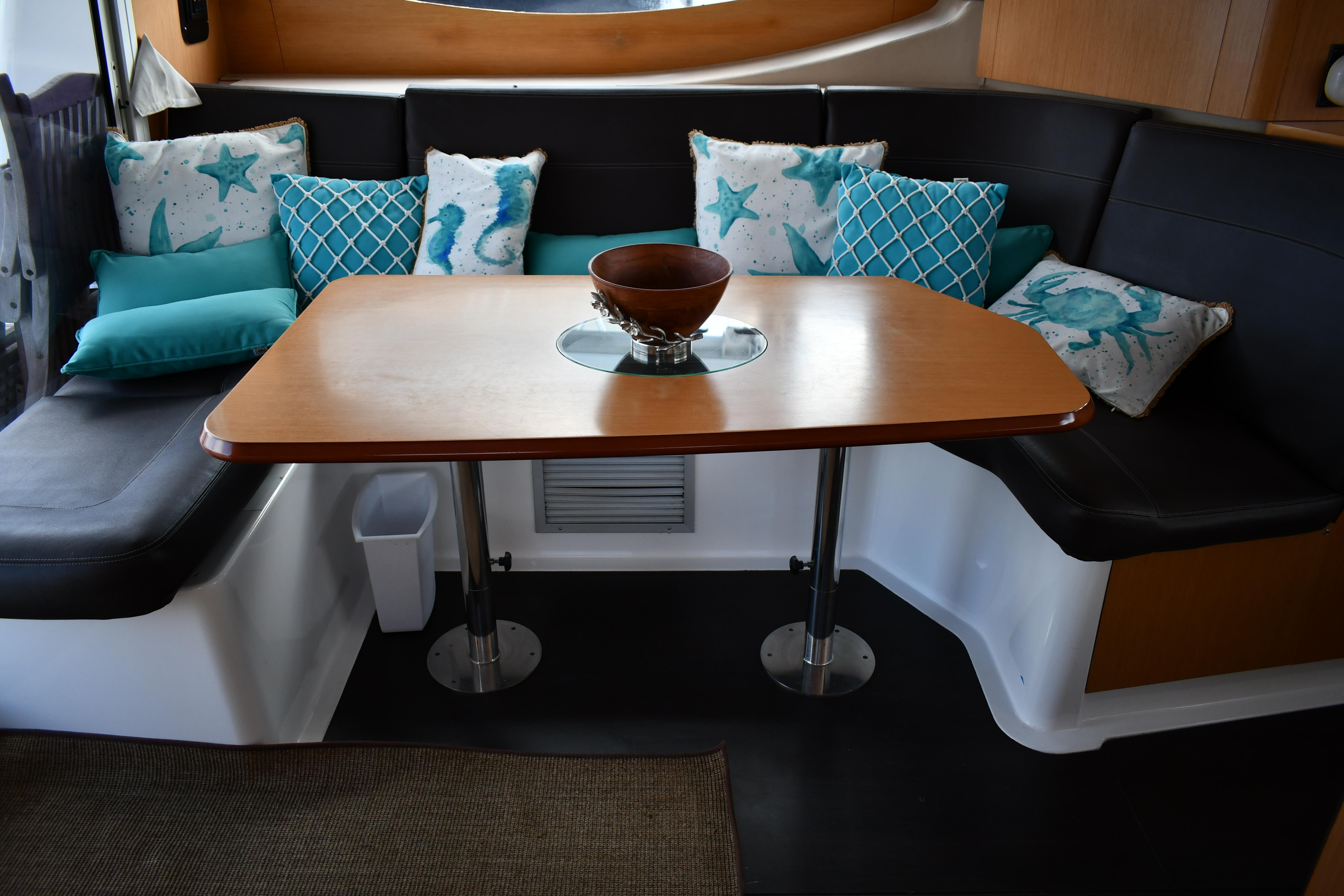 Cozy dining area in 2012 Fountaine Pajot 40 catamaran with decorative pillows and wooden table.