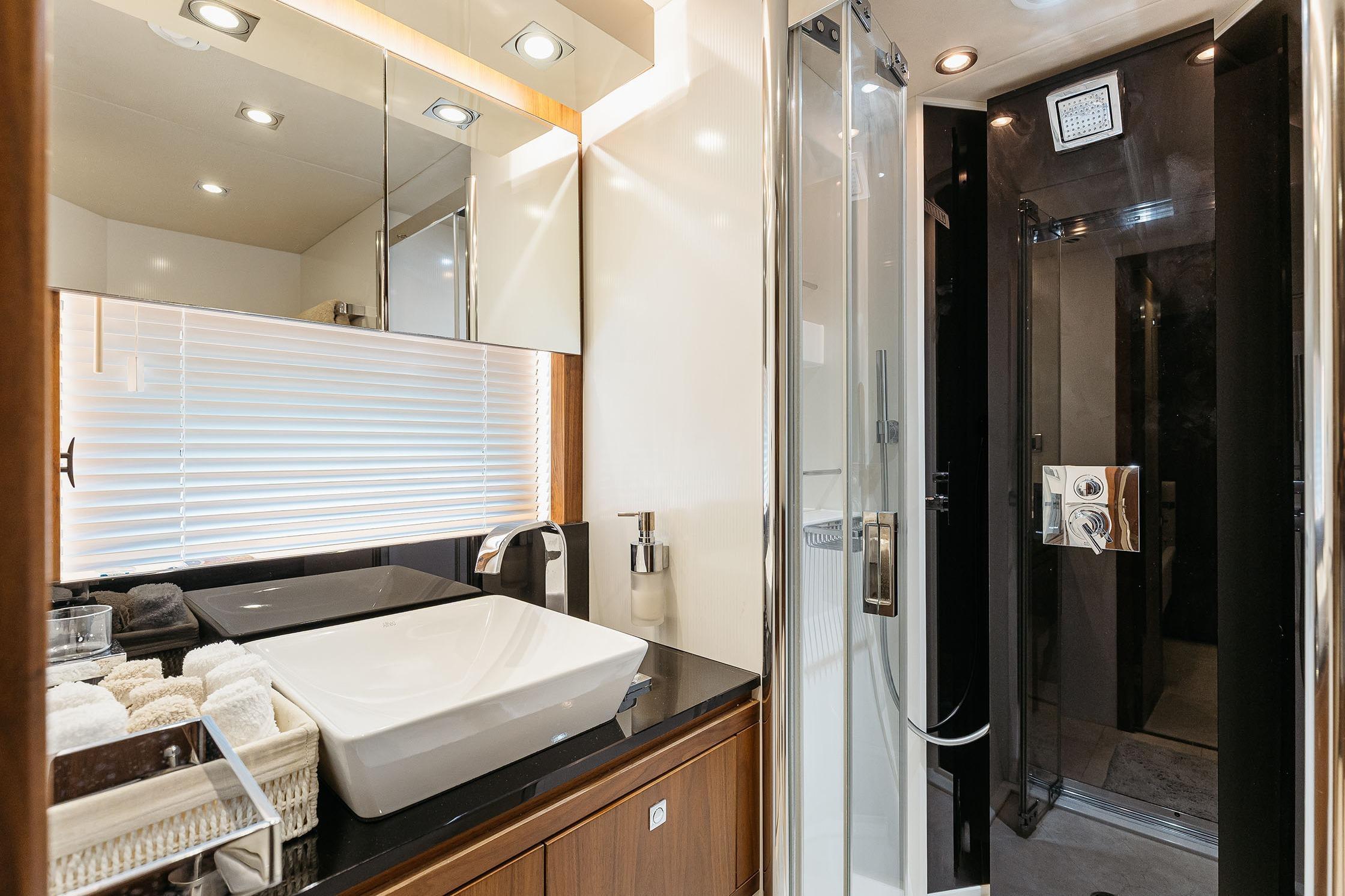 Luxurious bathroom in 2009 Sunseeker Predator 92 yacht, featuring modern sink and shower.