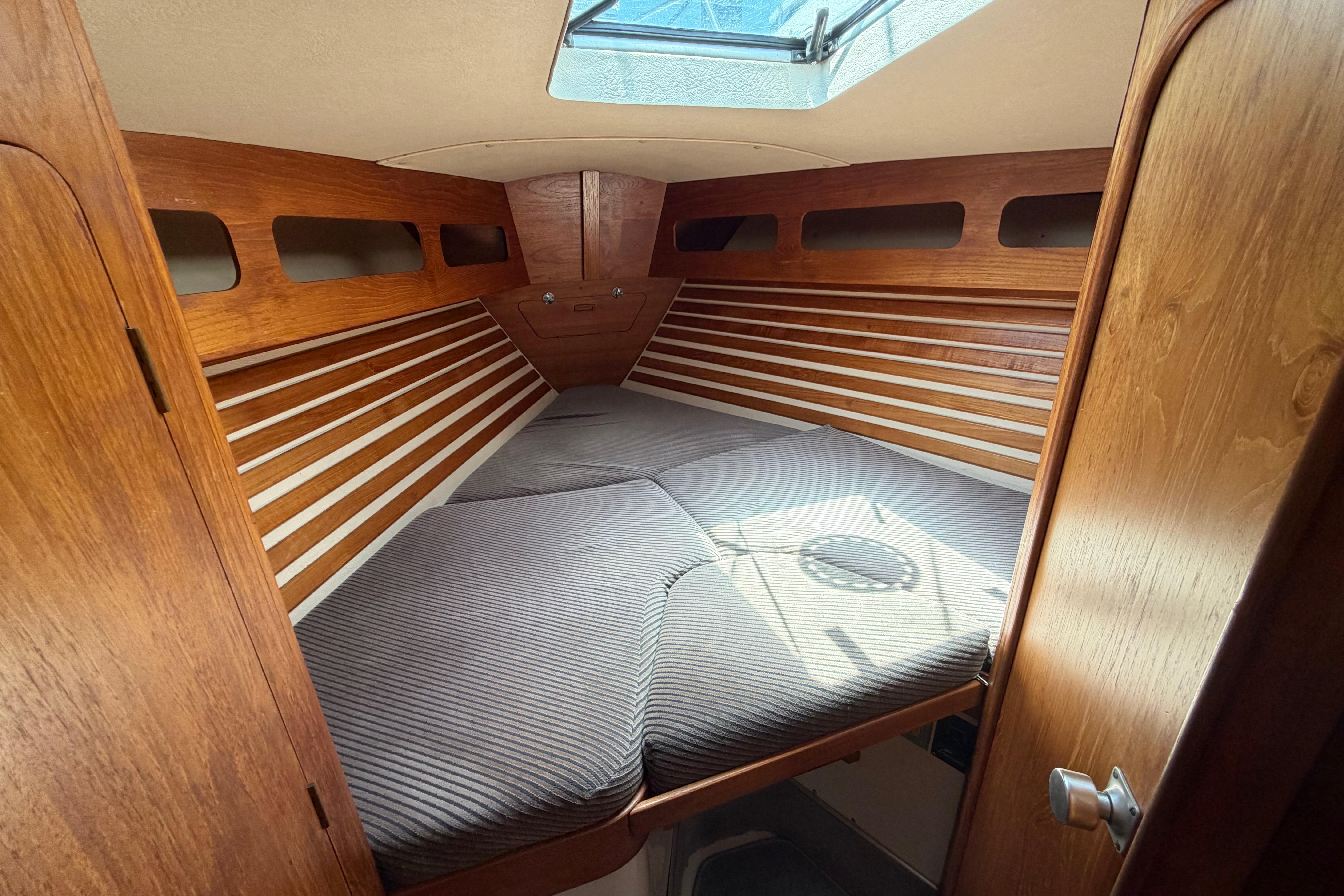 Cozy cabin interior of a 1987 Moody 376 sailboat with wooden accents and skylight.