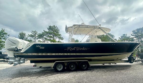 2008 SeaVee 390B boat on trailer, dark hull, triple engines, overcast sky.