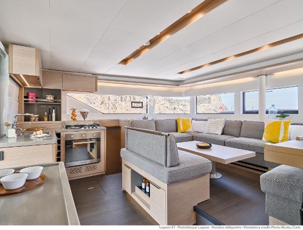 Luxurious interior of 2025 Lagoon 51 ICONIC yacht with modern kitchen and spacious seating area.