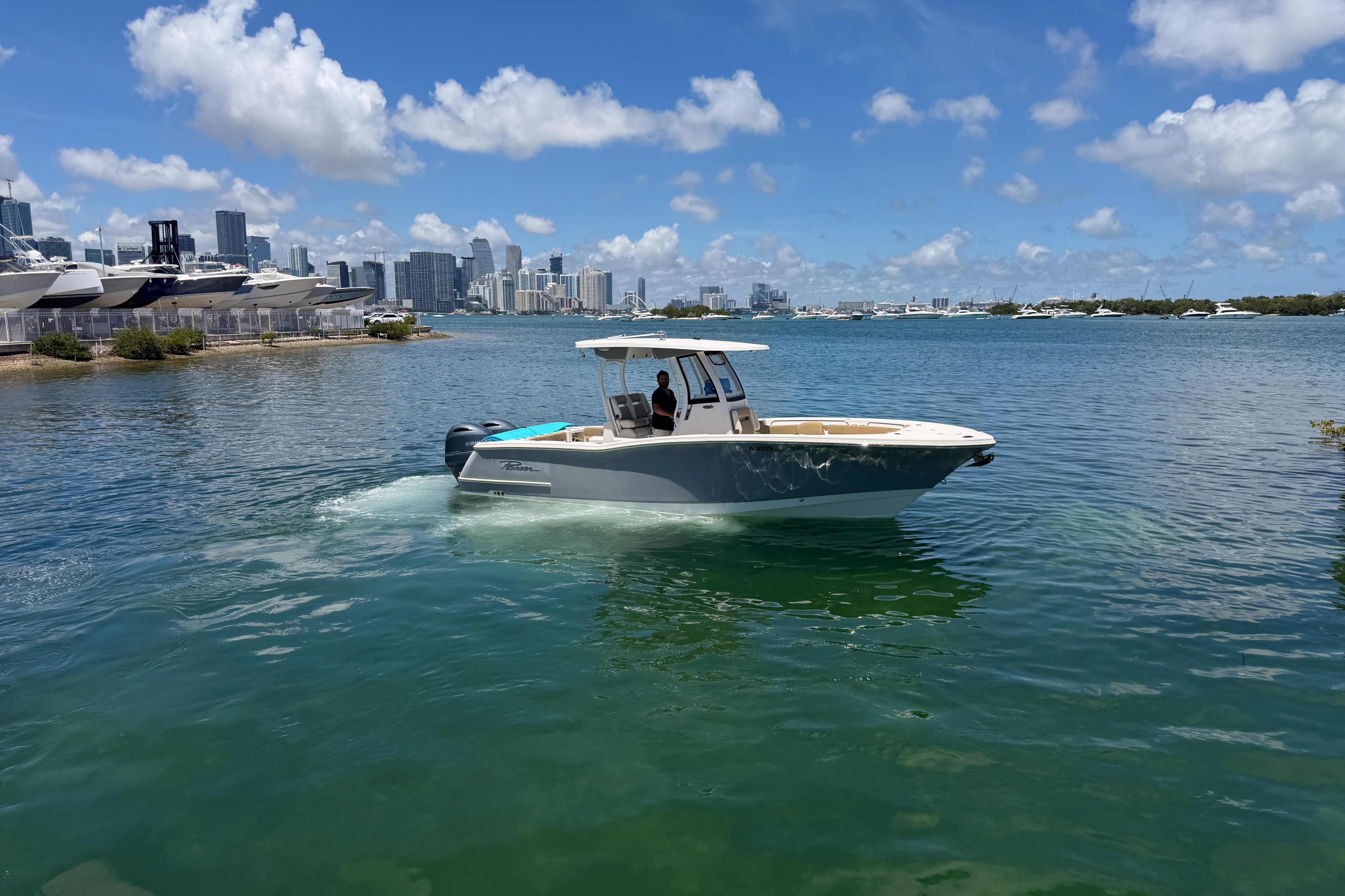 2019 Pioneer 266 Pelagic boat cruising near city skyline under blue sky.