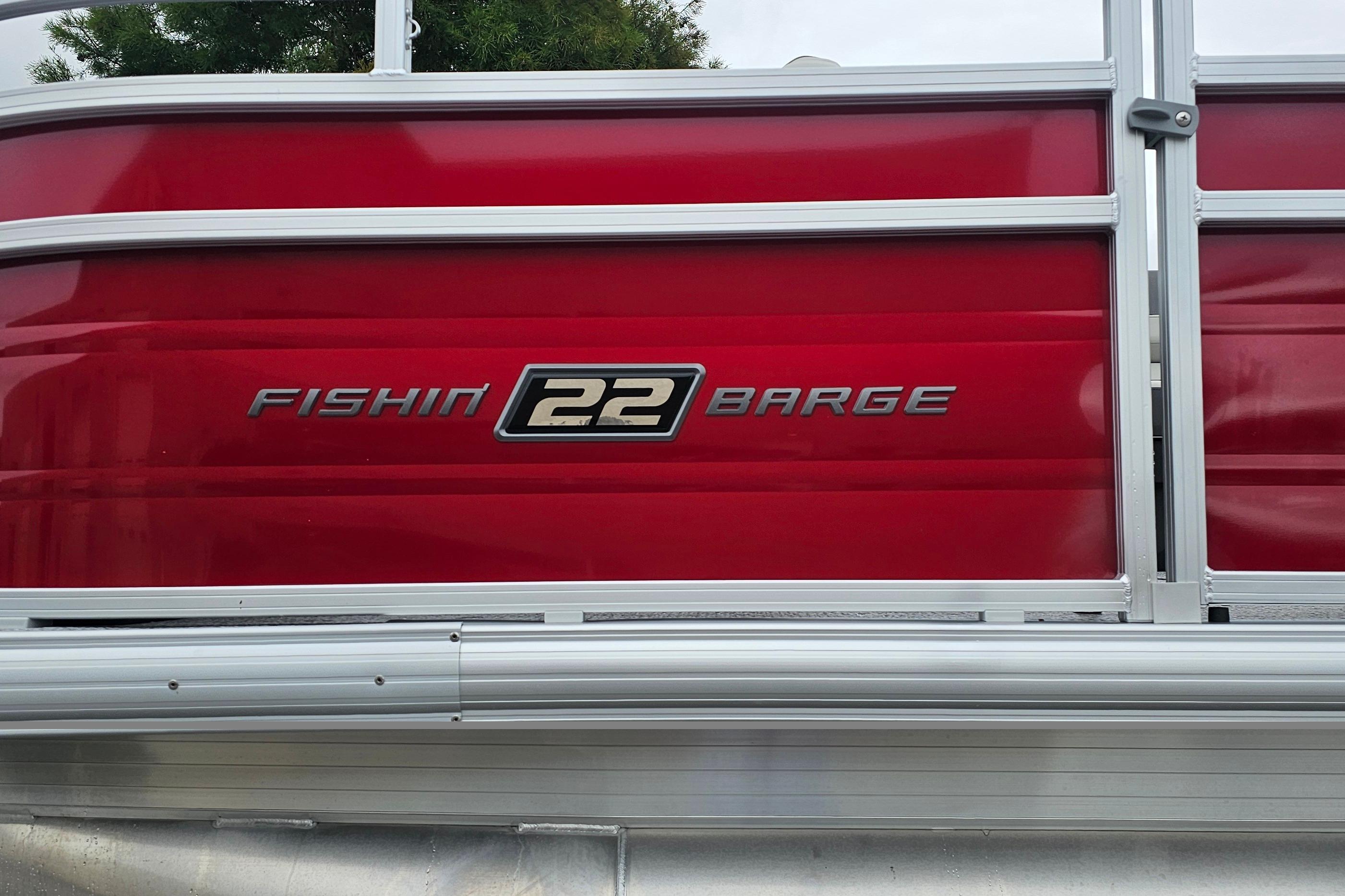 Red 2026 Sun Tracker Fishin' Barge 22 DLX pontoon boat side view.