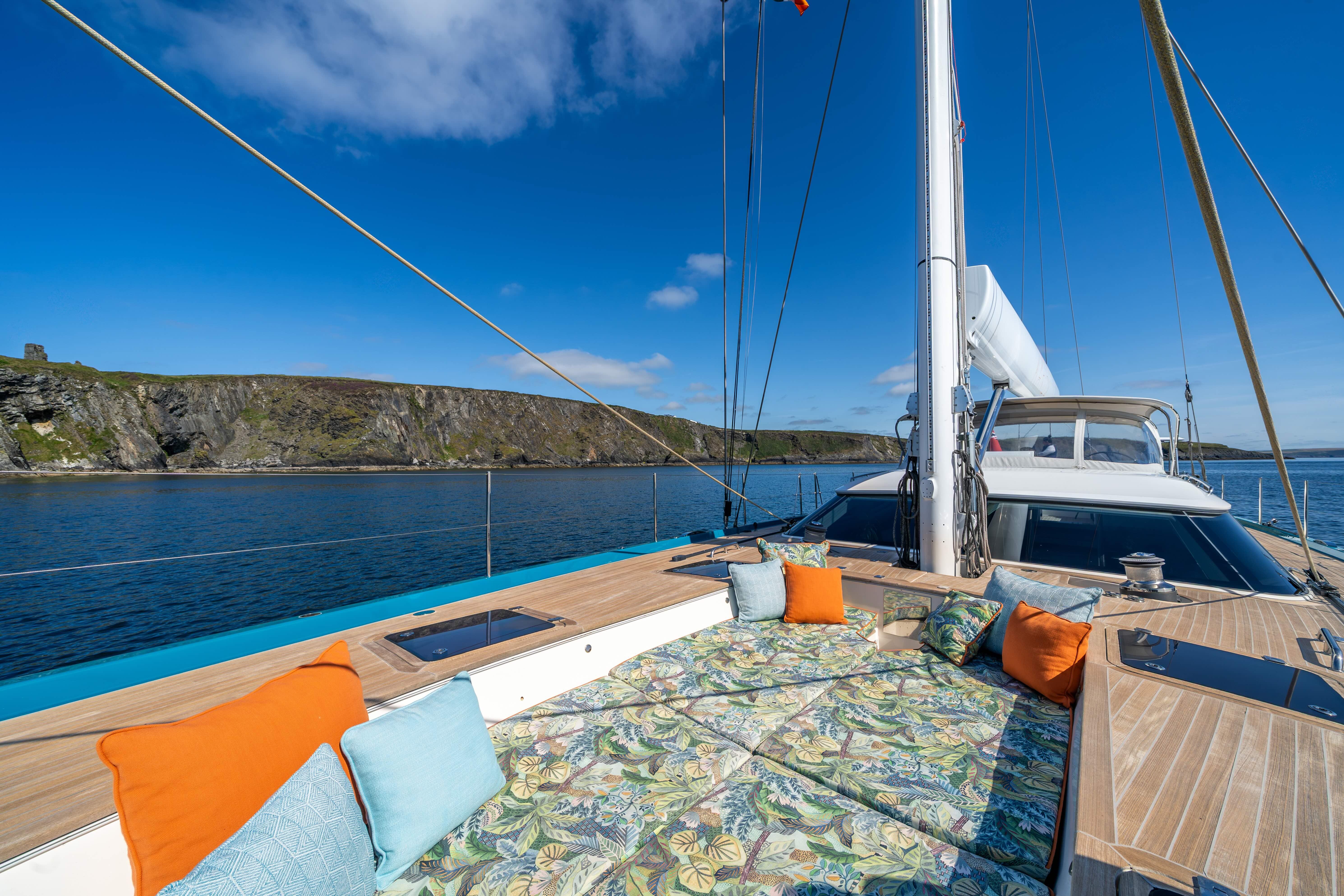 Luxurious 2013 Oyster 885 yacht deck with colorful cushions, scenic coastal view.