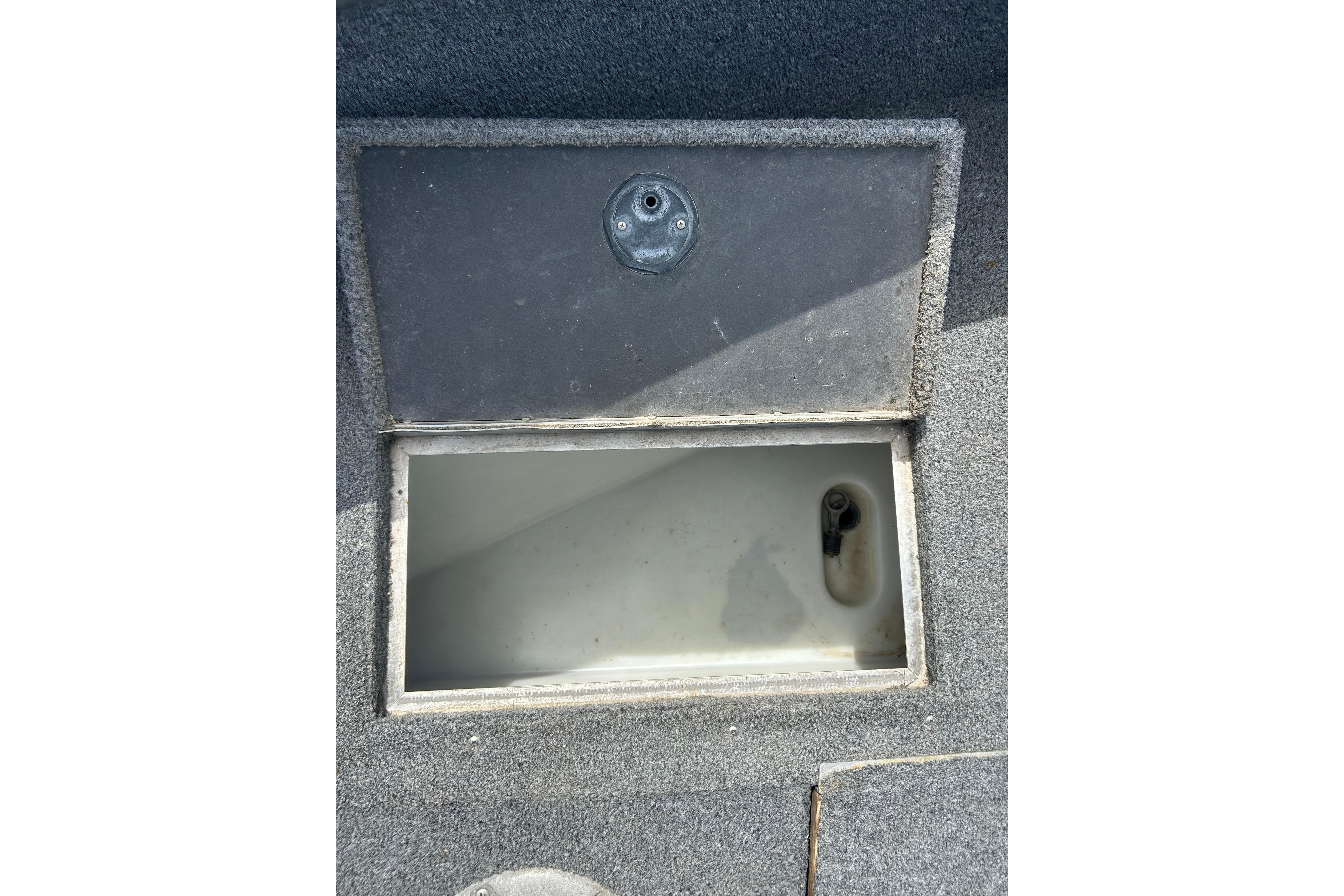 Open storage compartment on 2008 Lund 1850 Fisherman boat, featuring gray carpeted interior.