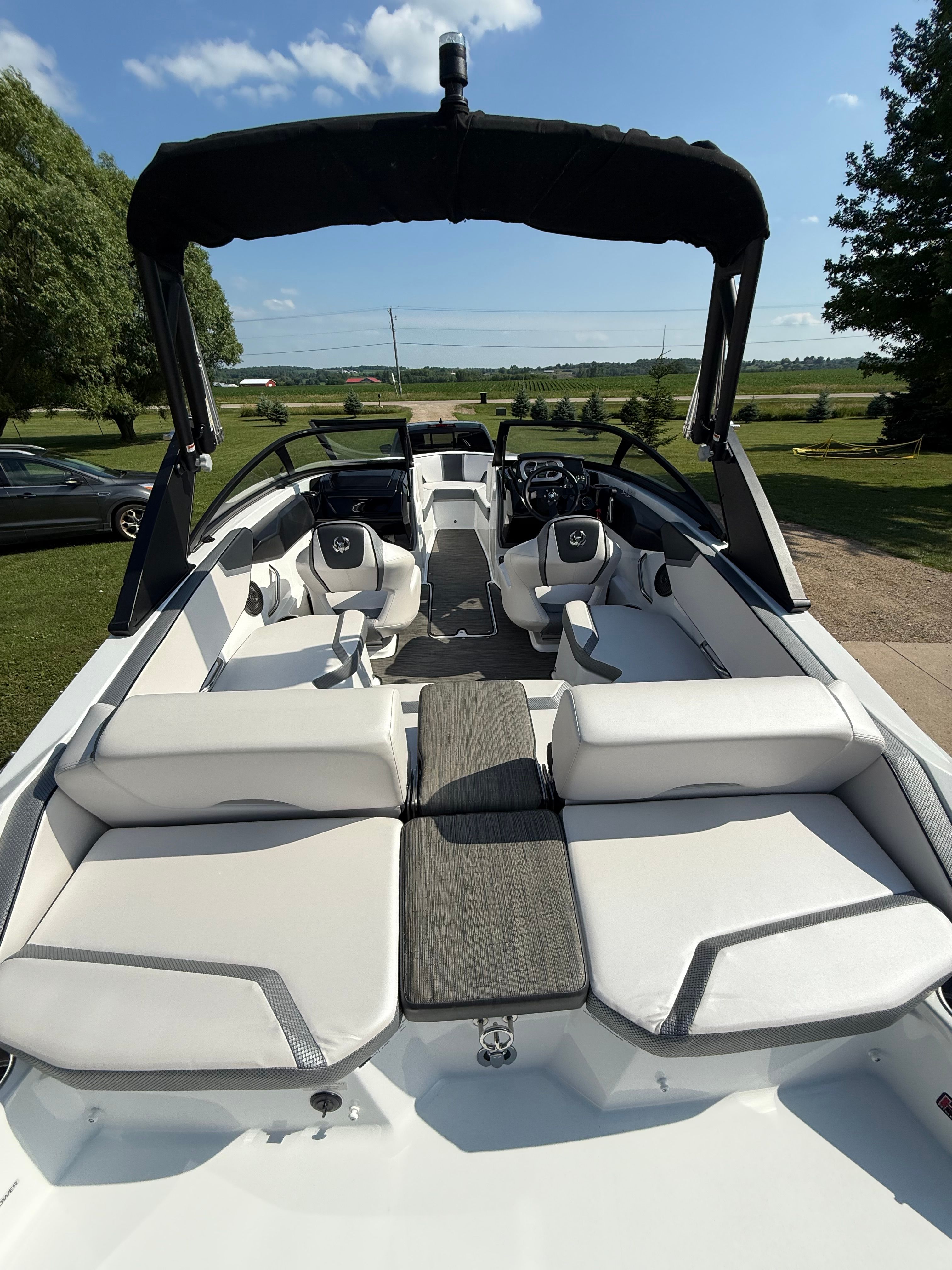 The image shows the cockpit of a 2023 Scarab 195 ID boat with white seating and a black canopy.