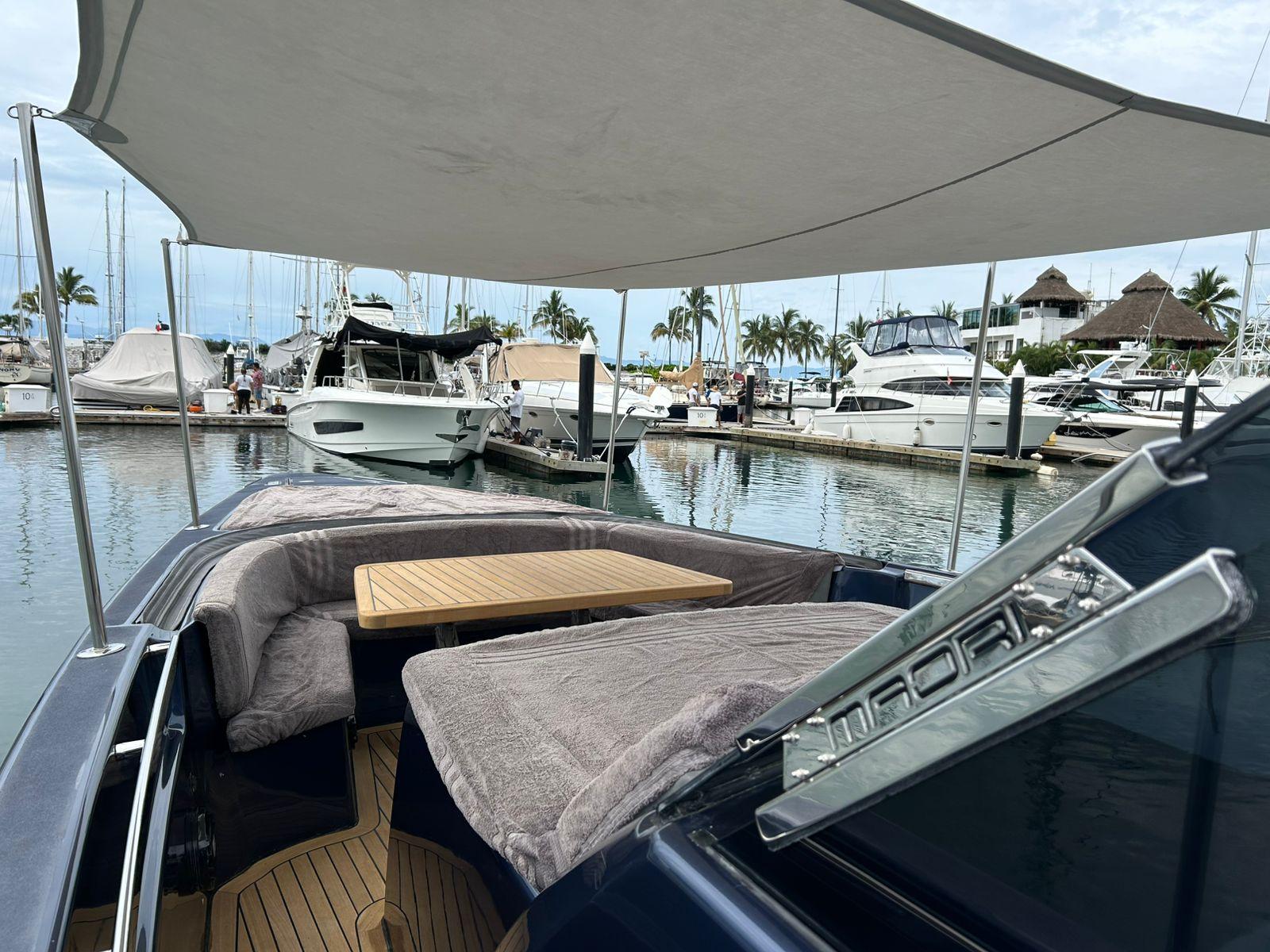Luxury Maori 50 yacht docked at marina, featuring shaded seating and wooden table, 2016 model.