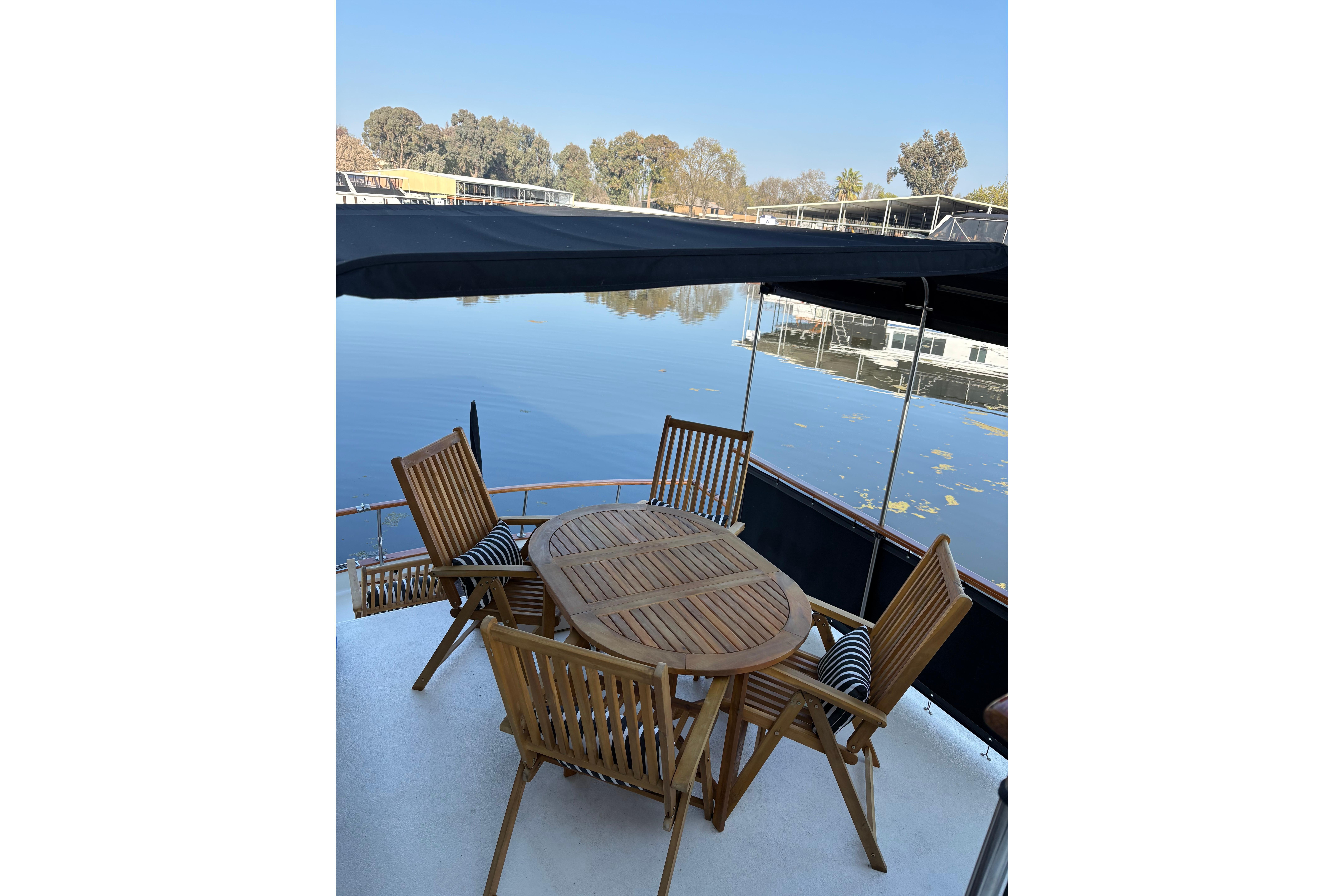 Outdoor dining area on 1978 Californian 42 LRC yacht, overlooking serene water.