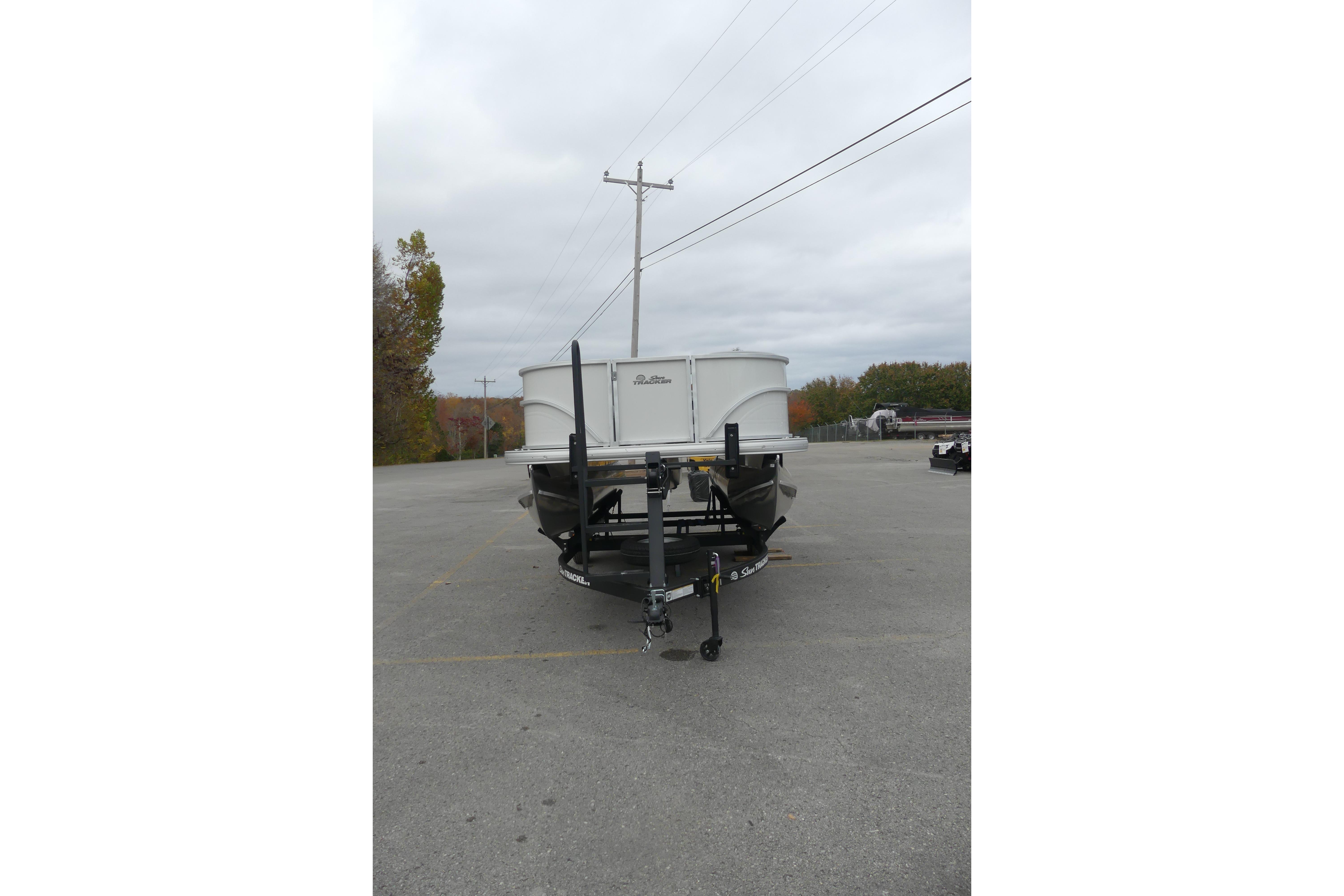 2026 Sun Tracker Party Barge 16 DLX pontoon boat on trailer in parking lot.