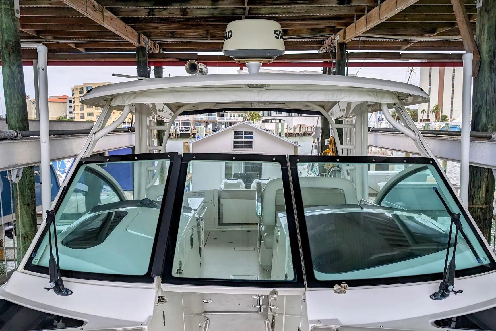 2017 Boston Whaler 320 Vantage boat docked under a wooden shelter.