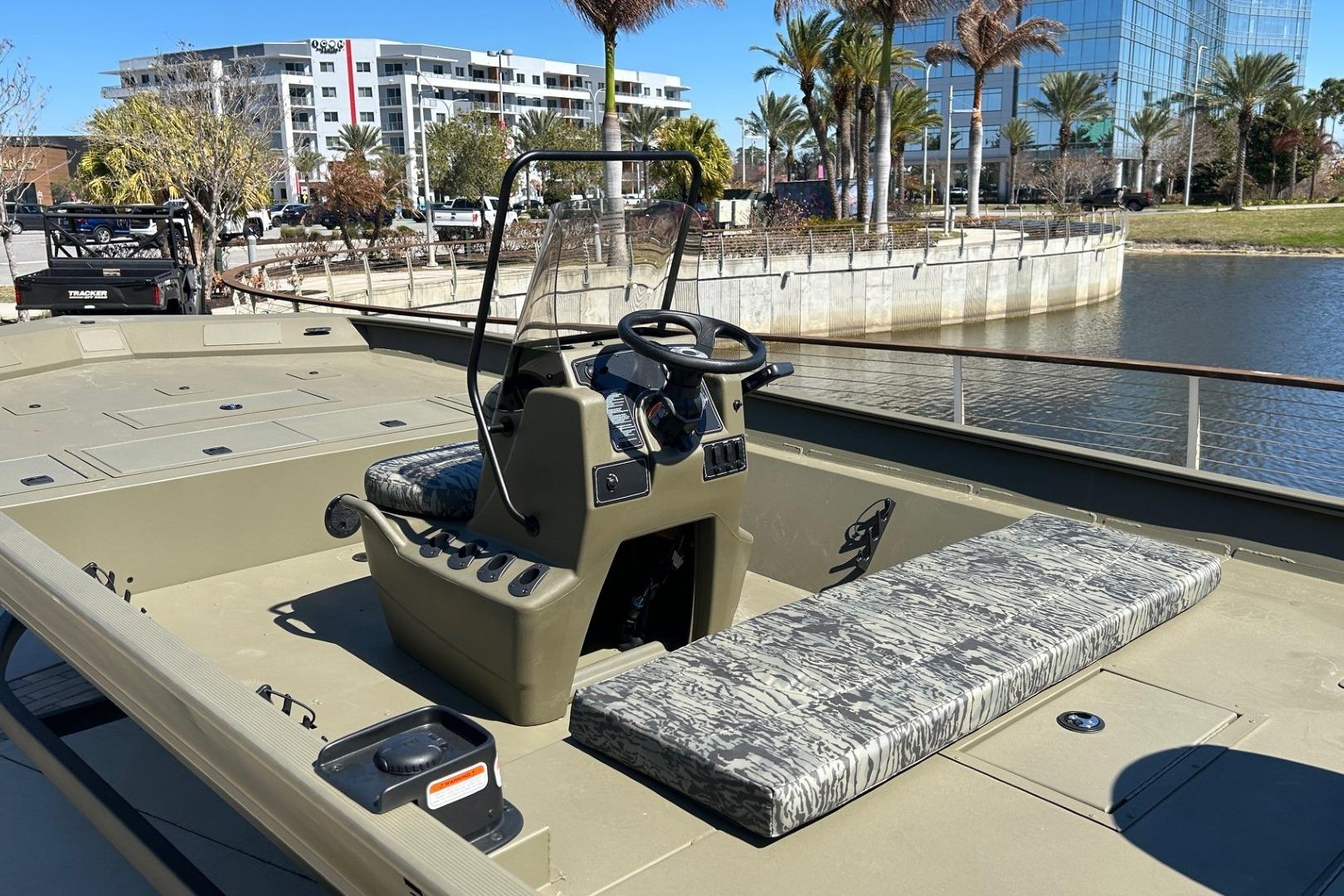 2026 Tracker Grizzly 2072 CC boat docked by waterfront with modern buildings and palm trees.