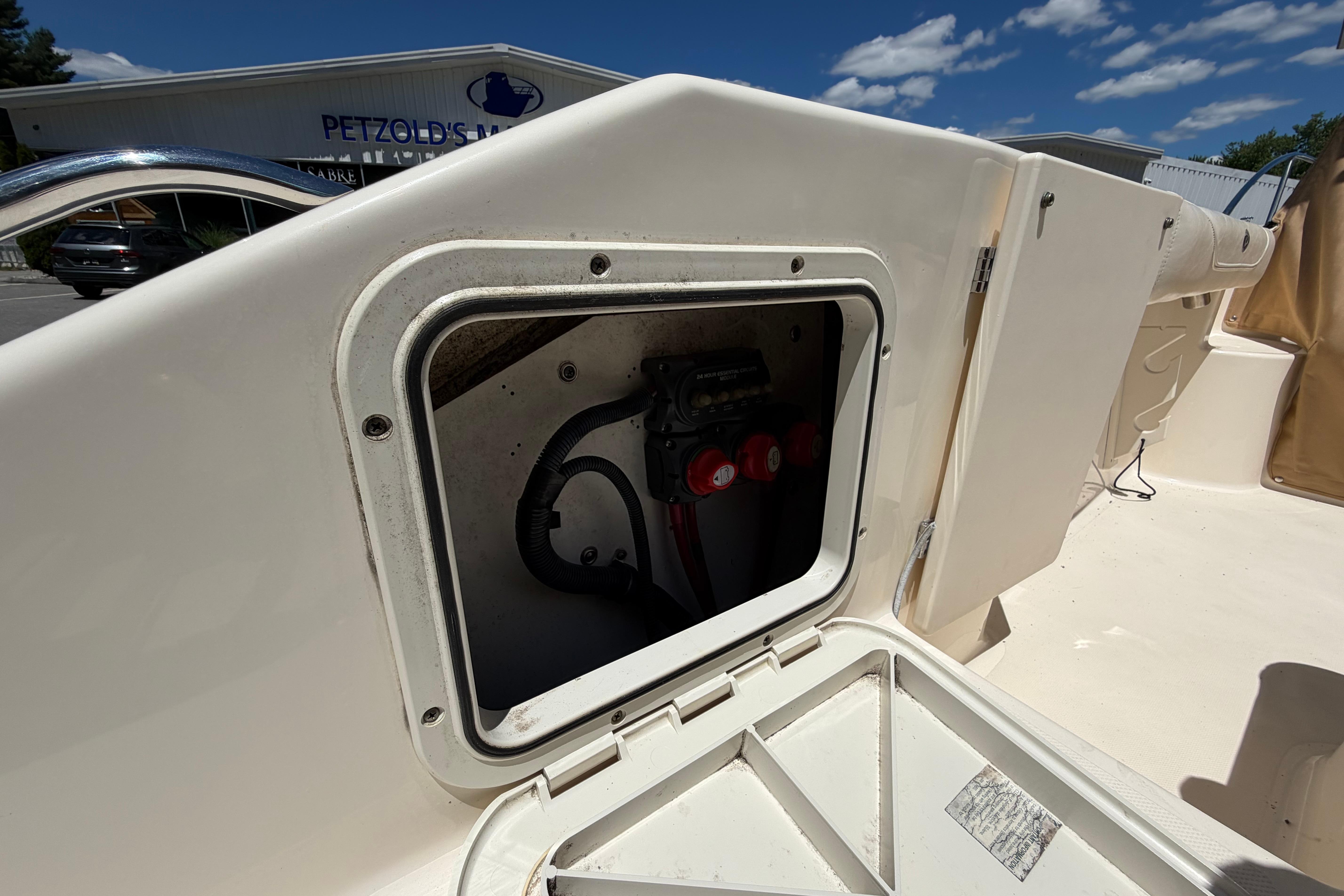 2010 Pursuit OS 255 Offshore boat compartment with wiring, under clear blue sky.