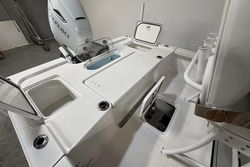 2026 Sea Pro 250 Bay boat interior with Suzuki engine, featuring storage compartments and rod holders.