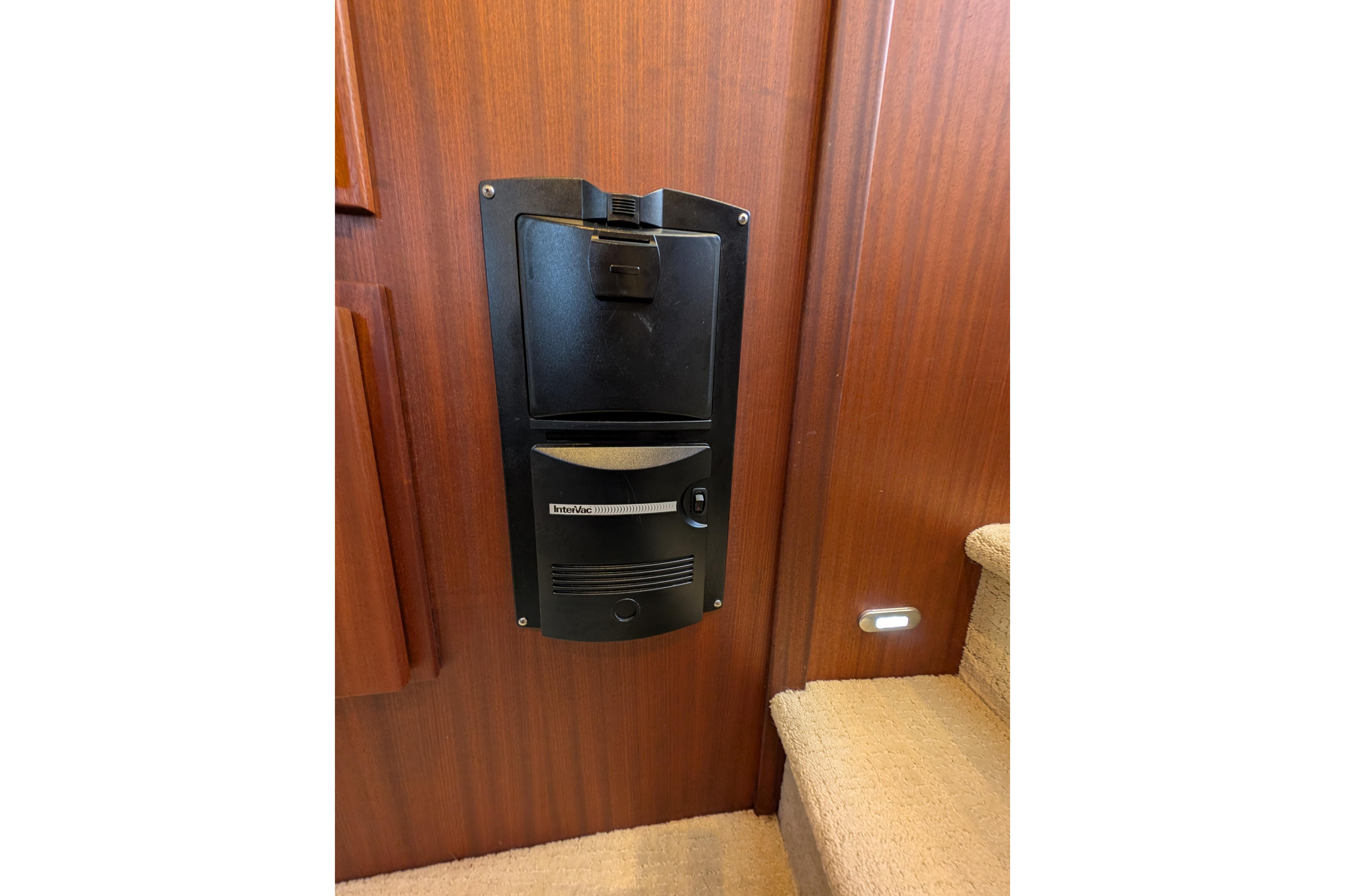 Built-in vacuum system on 2015 American Tug 435 yacht, mounted on wooden wall near stairs.