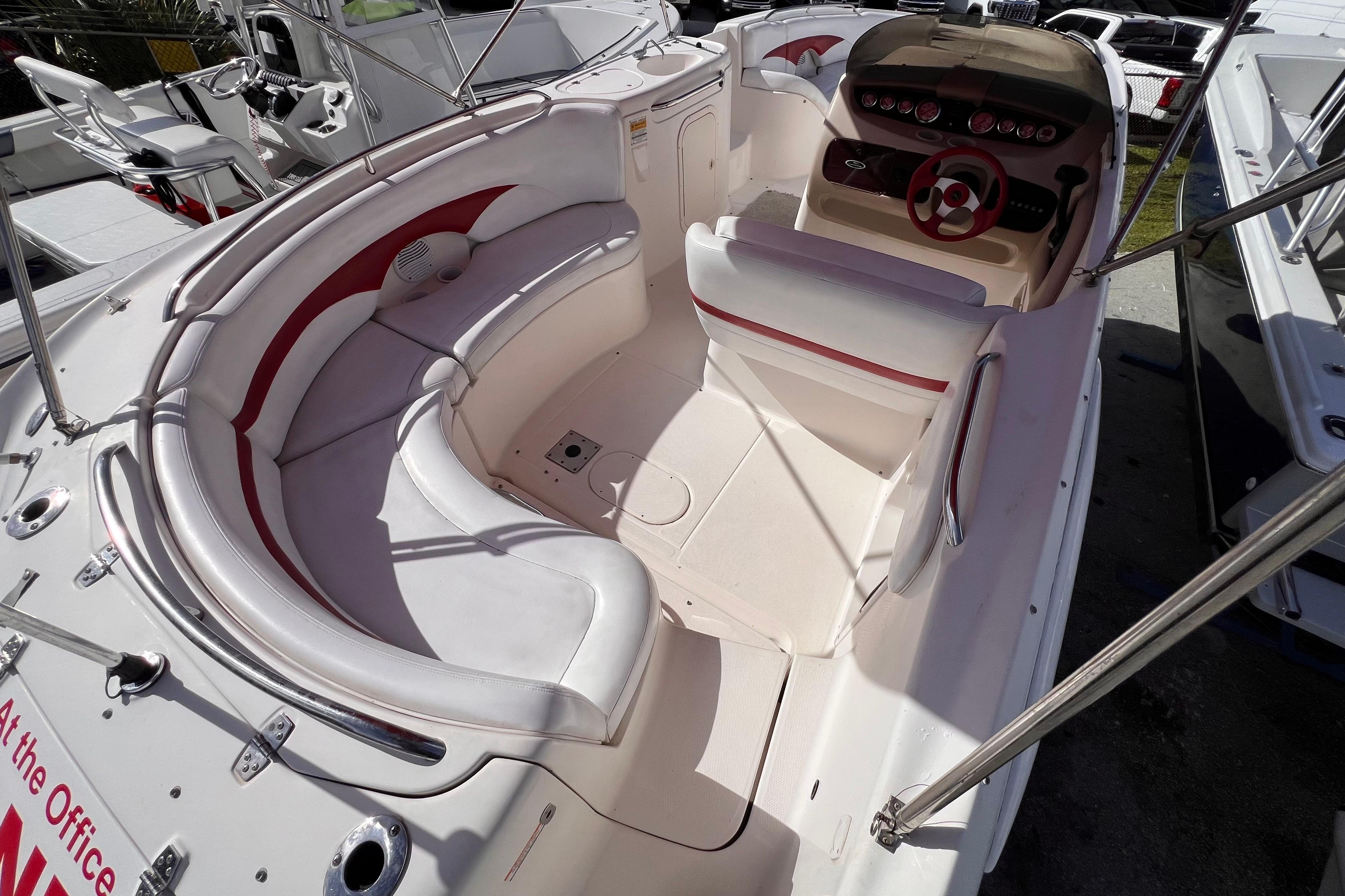 2002 Chaparral 232 Sunesta boat interior with white and red seating, steering wheel, and dashboard.