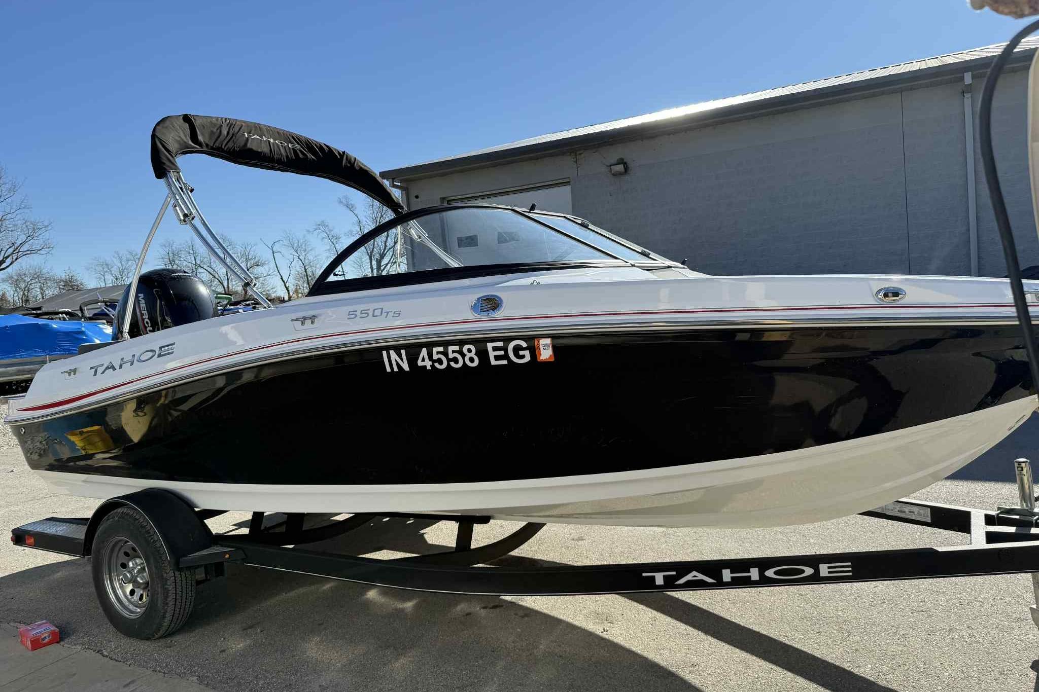2021 Tahoe 550 TS boat on trailer, black and white design, parked outdoors.