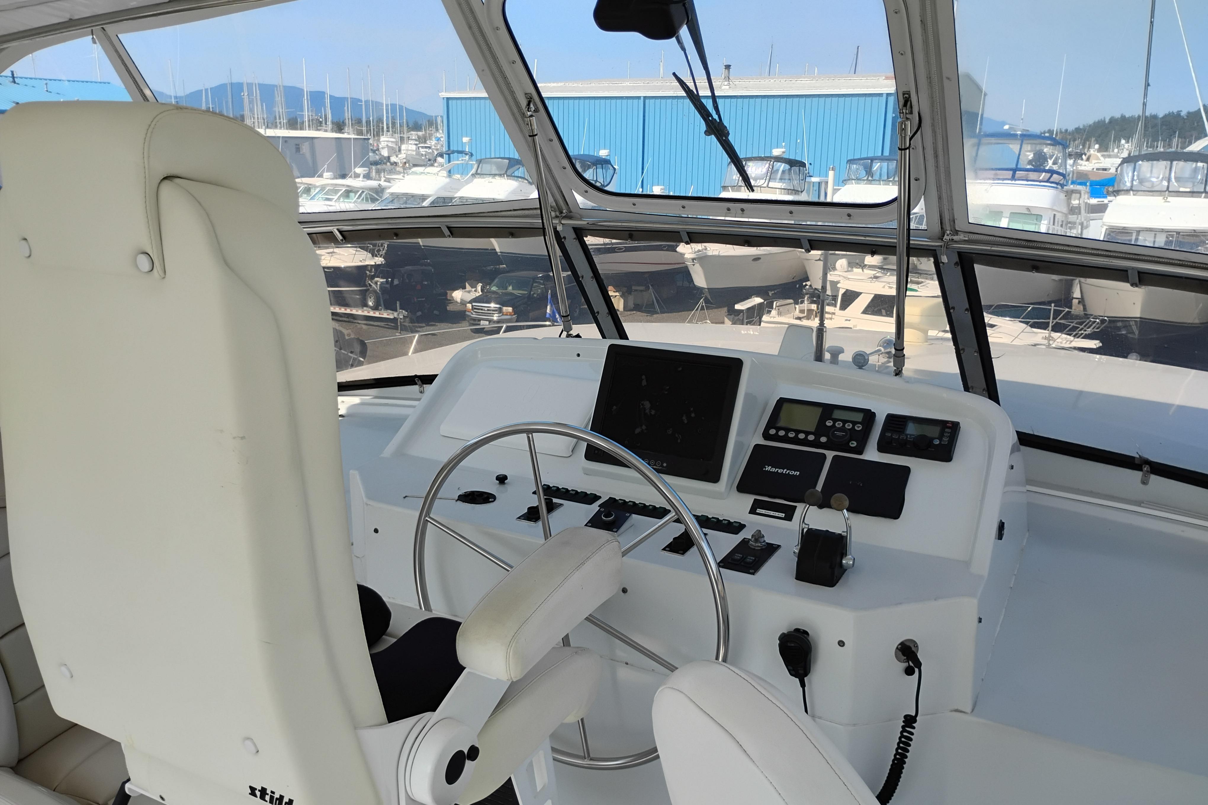 Pilothouse of 1995 Queenship 62 Motor Yacht with steering wheel and navigation controls.