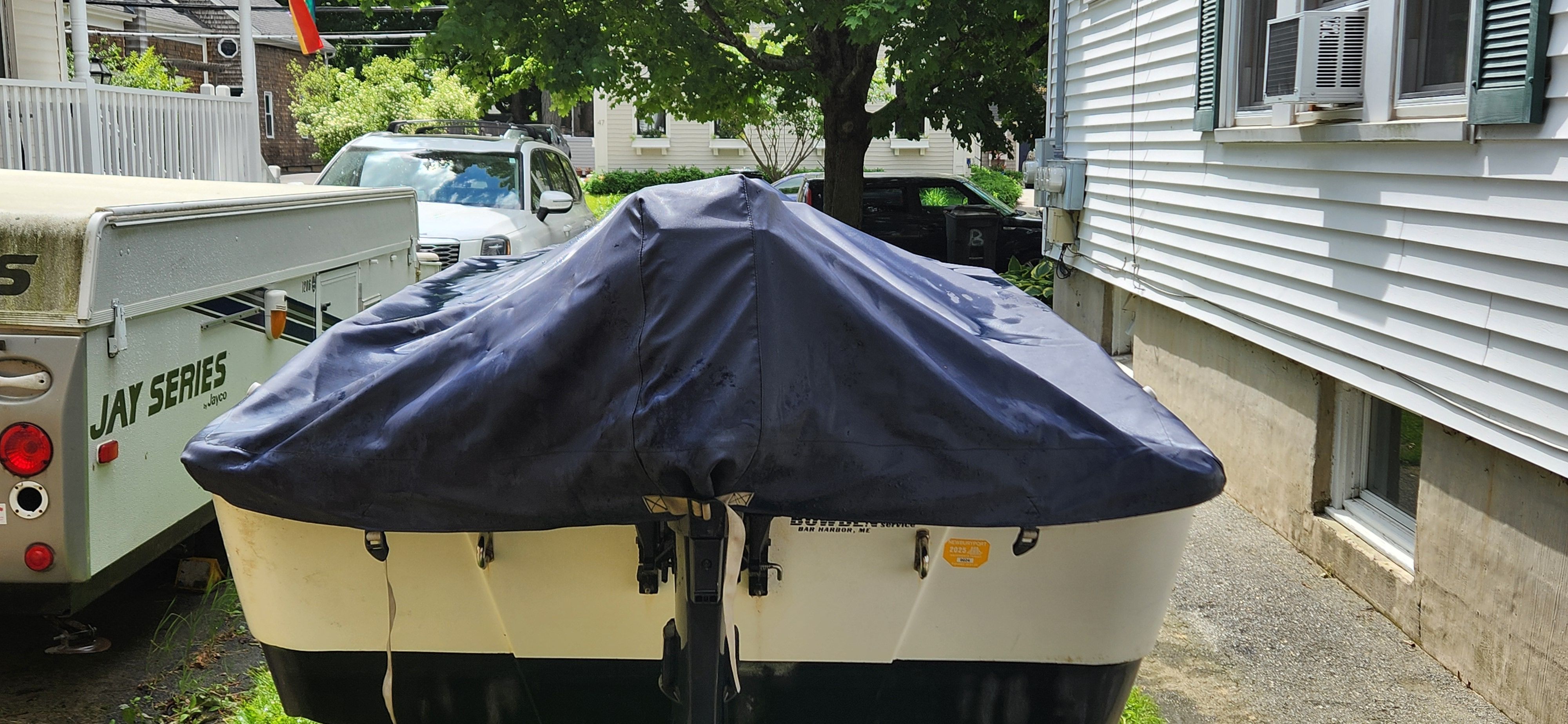 A 2005 Boston Whaler 110 Sport boat is on a trailer in a driveway.