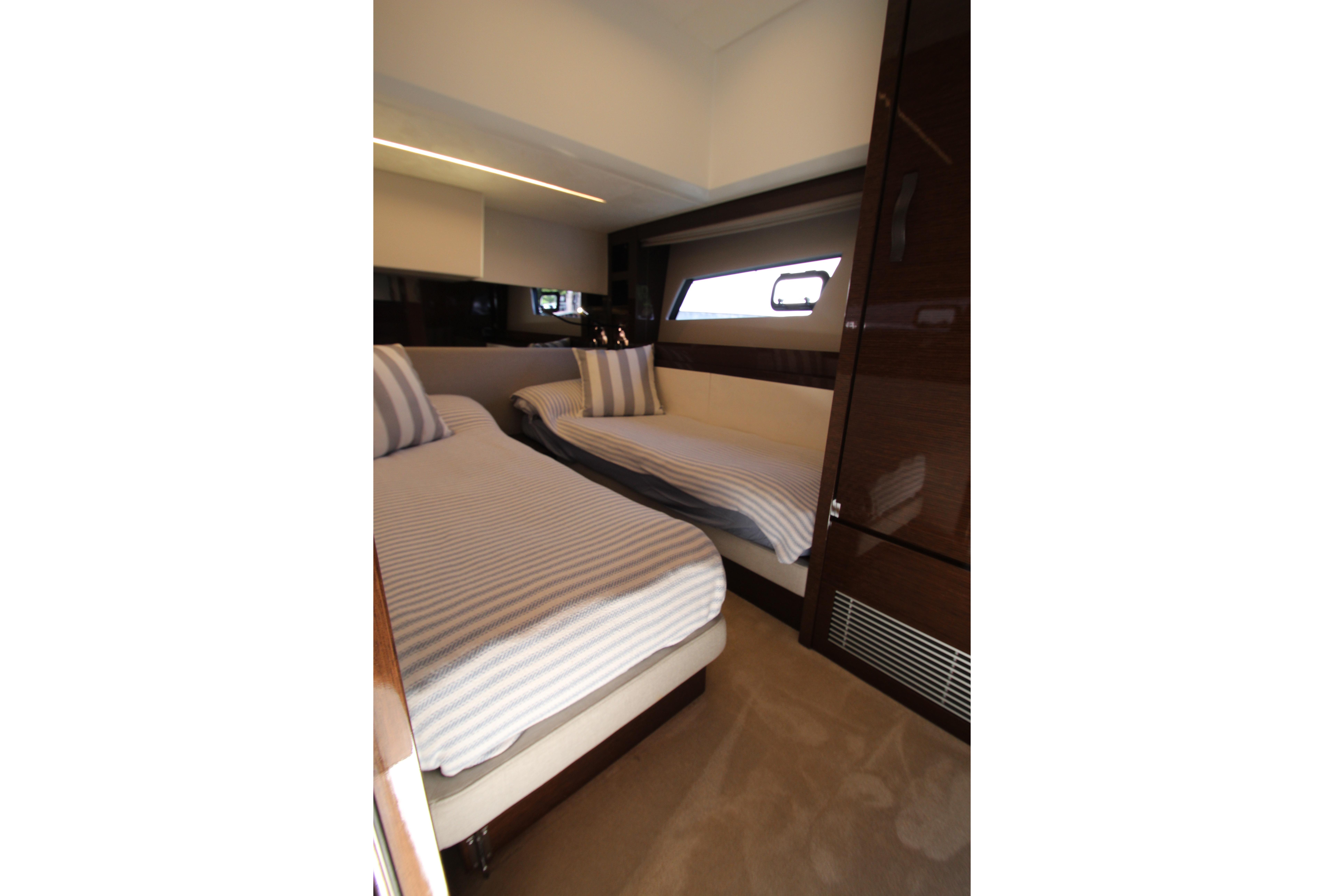 Luxurious twin cabin interior of 2022 Prestige 520 yacht with striped bedding.
