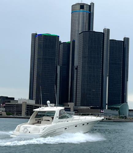 2003 Sea Ray 460 Sundancer cruising near modern skyscrapers on a cloudy day.