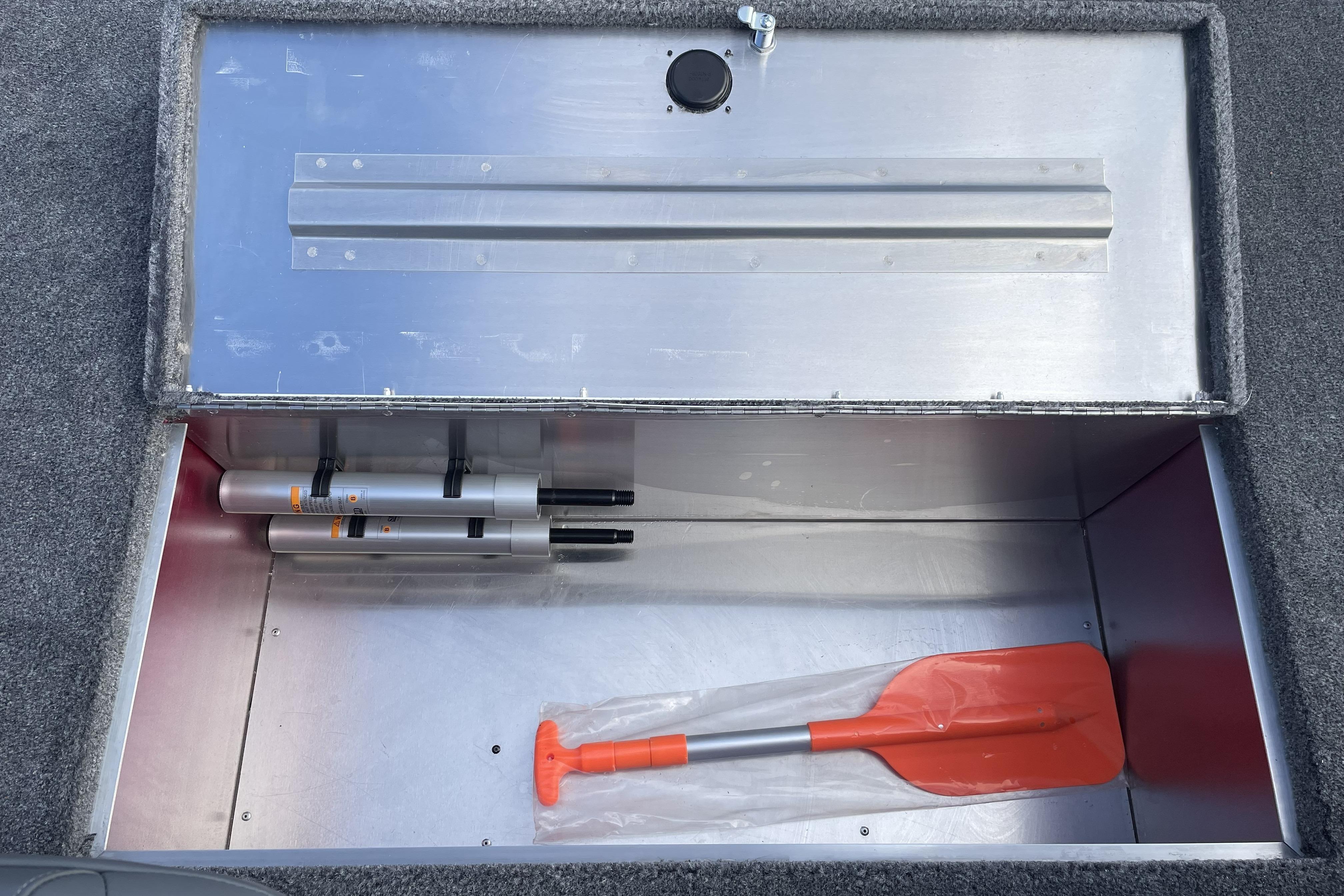 Storage compartment in 2026 Tracker Bass Tracker Classic XL boat with paddle and accessories.
