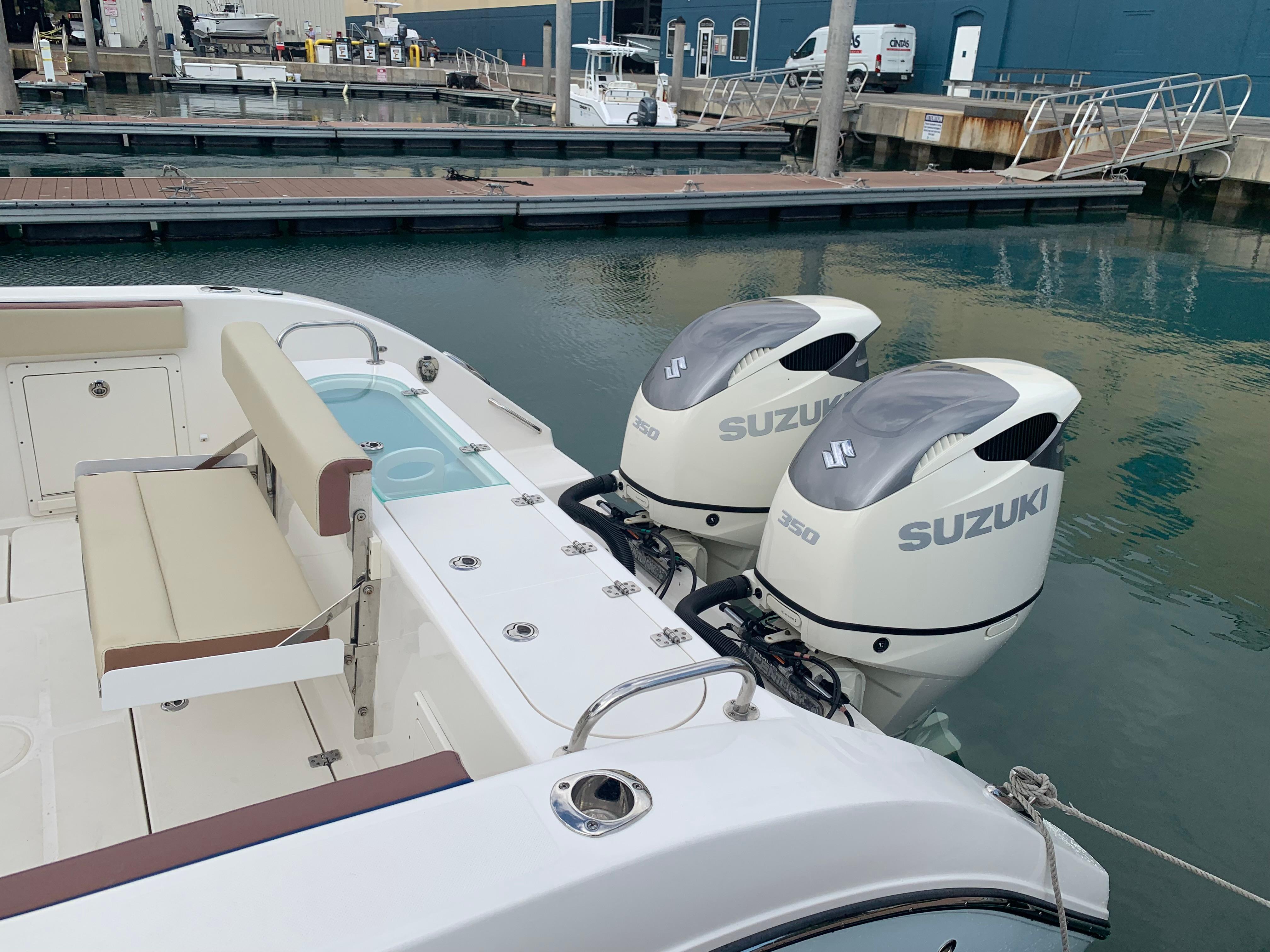 2019 Century 3200 Center Console with twin Suzuki outboard motors at a marina.