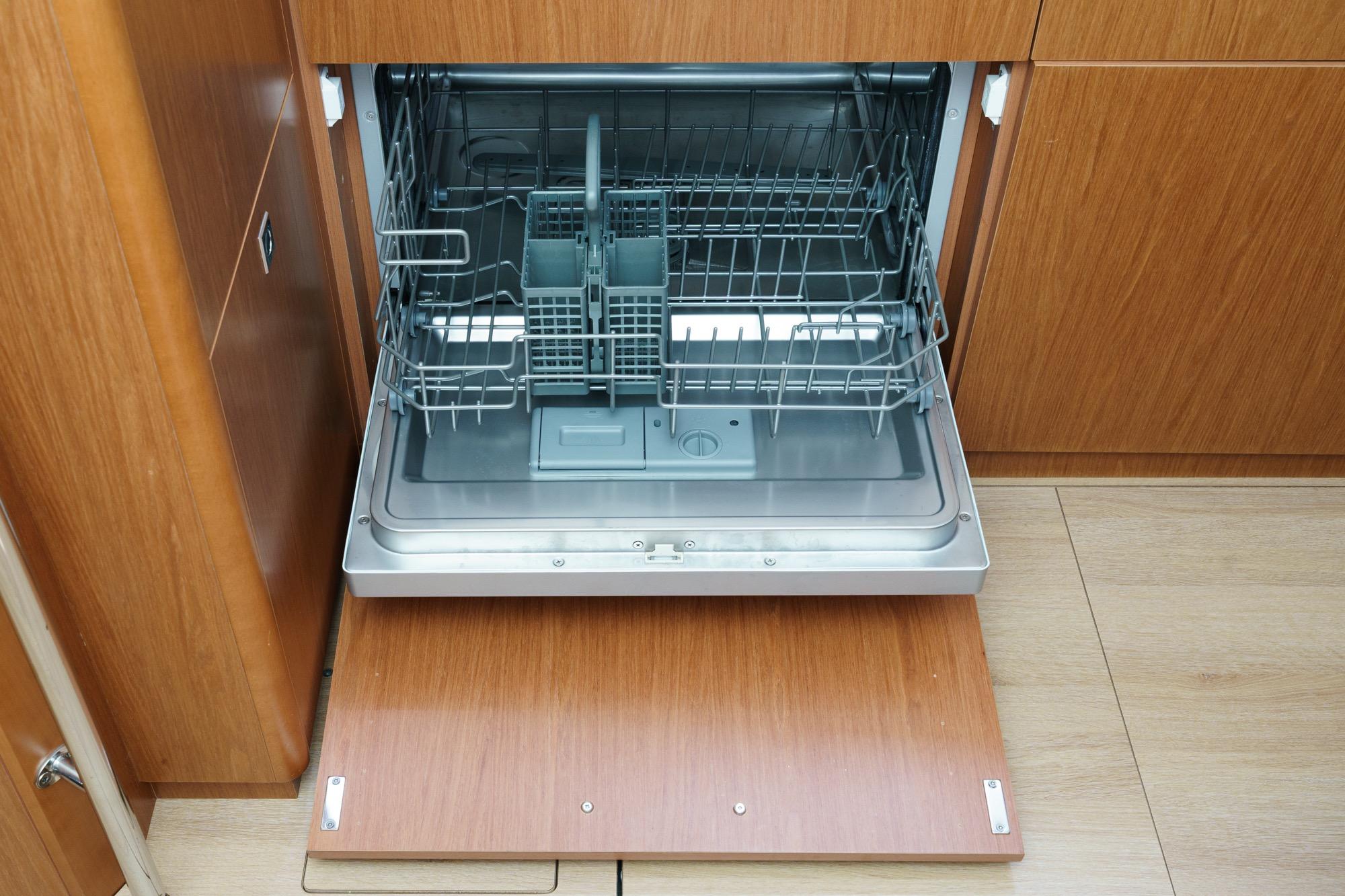 Open dishwasher in 2017 Beneteau Sense 50 yacht kitchen, featuring wooden cabinetry.