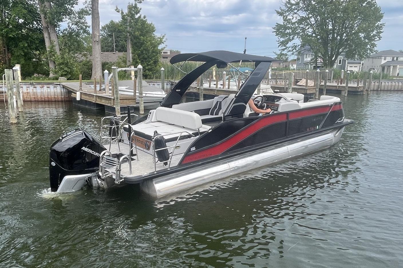 2024 Harris Grand Mariner 250 pontoon boat on water, featuring sleek design and Mercury outboard engine.