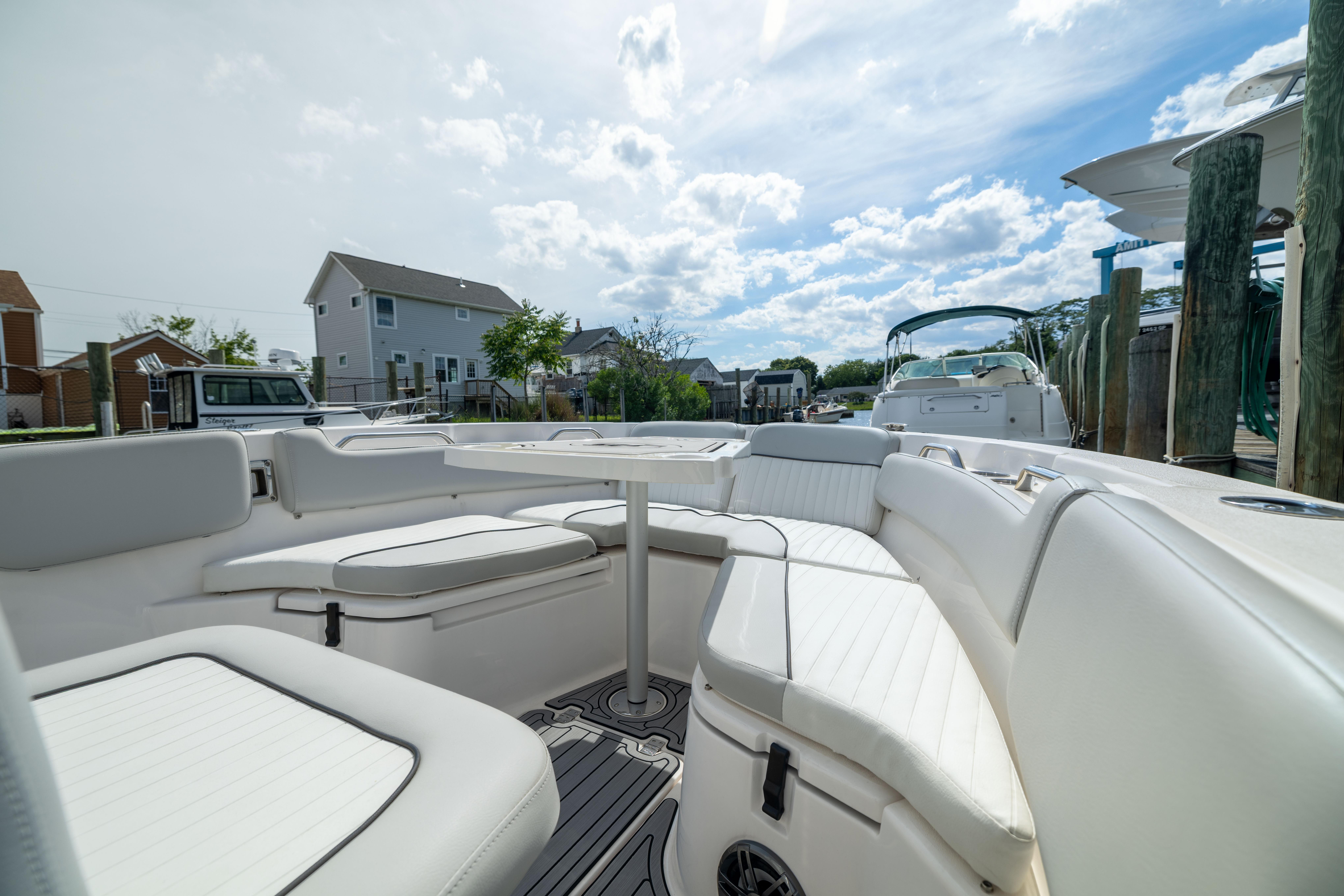2023 Sea Fox 228 Commander boat interior with white seating and table, docked under a cloudy sky.