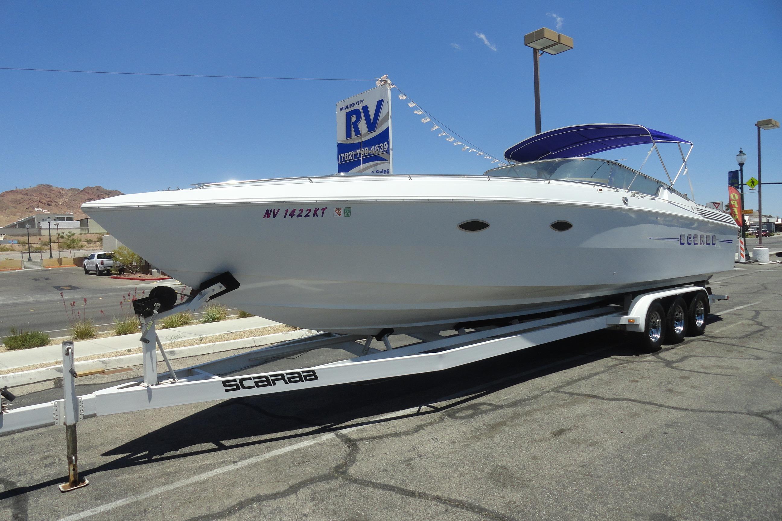 1988 Wellcraft 34 Scarab boat on trailer, parked outdoors under clear blue sky.