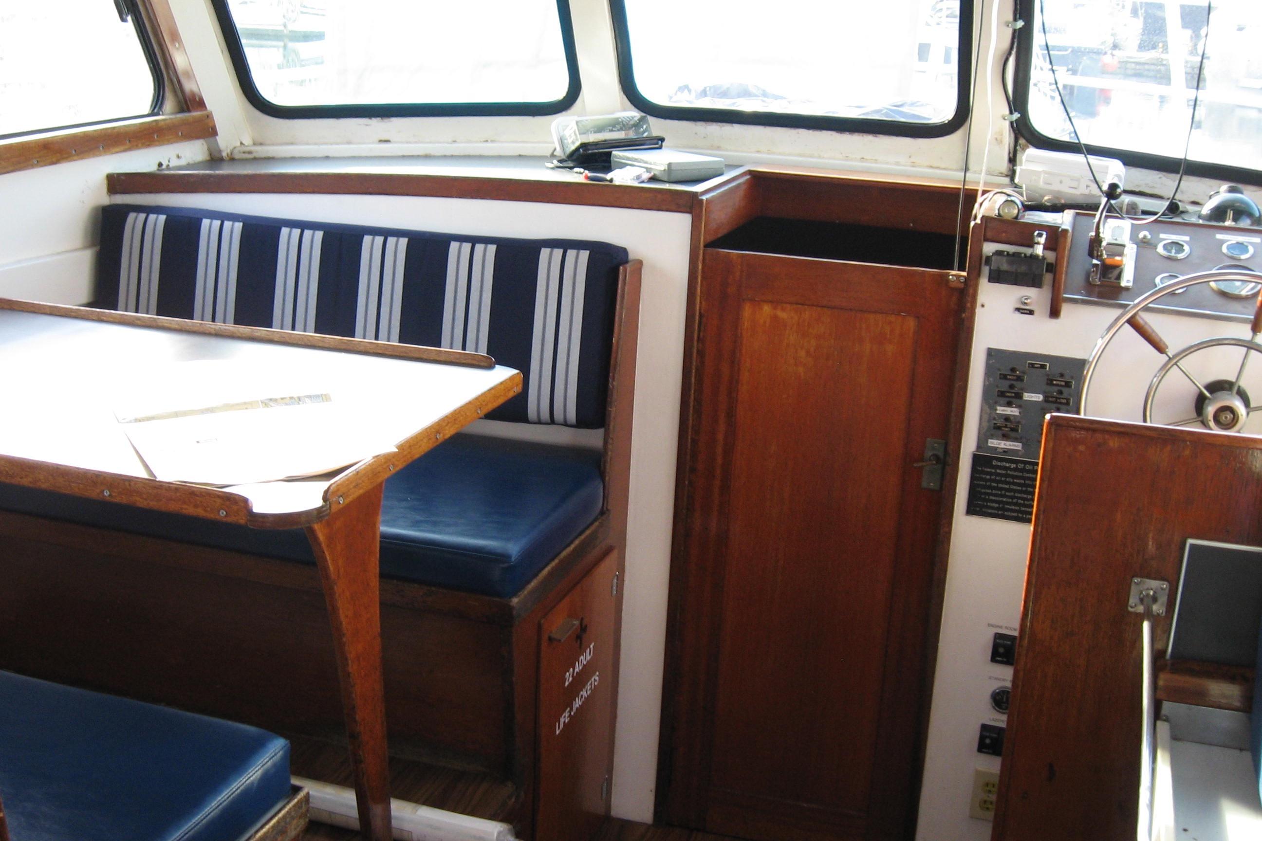 1964 Grandy Tour Boat interior with wooden helm, striped seating, and navigation controls.