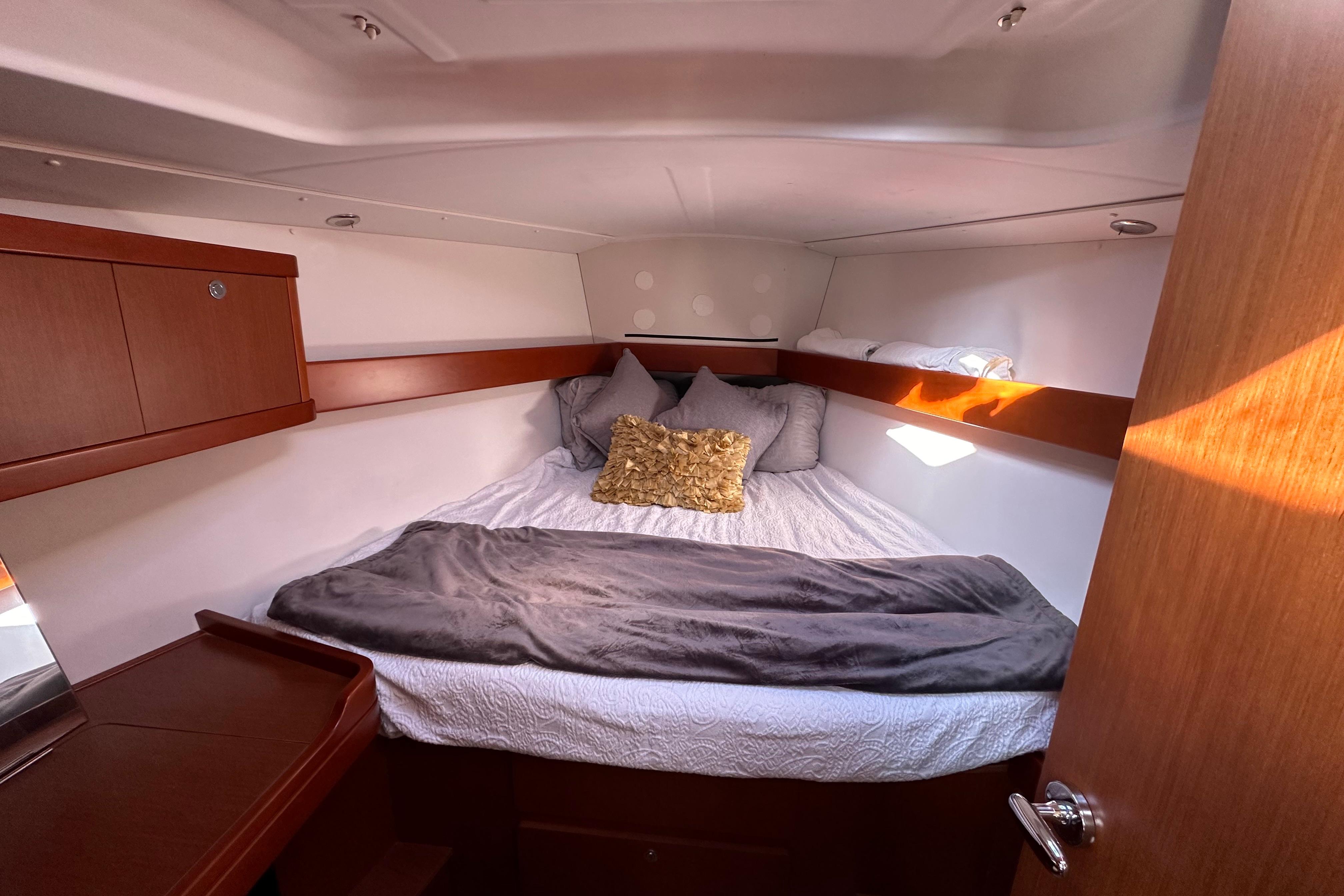 Cozy cabin interior of 2015 Beneteau Oceanis 37 sailboat with plush bedding and wooden accents.