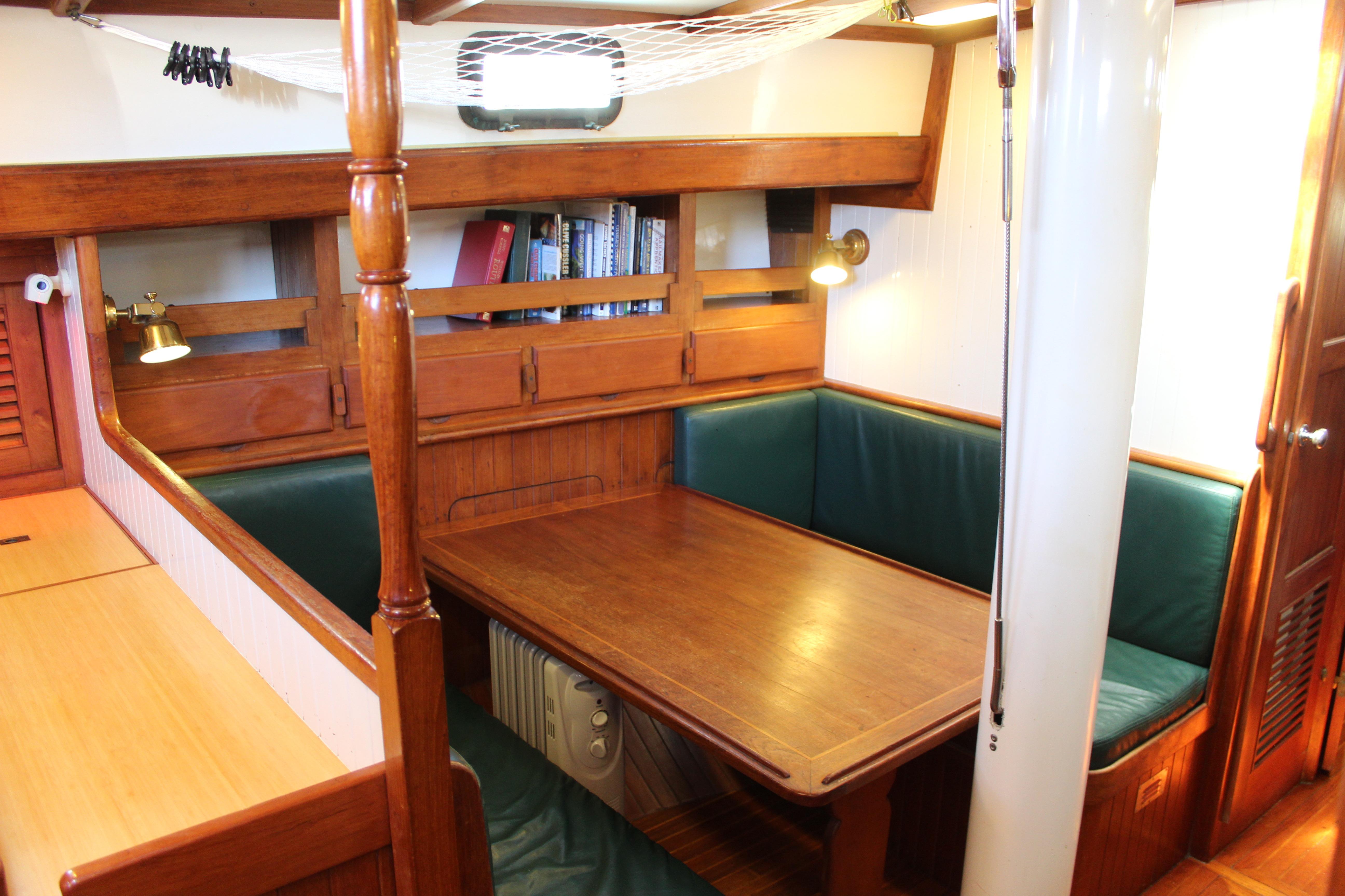 Interior of 1981 Kelly Peterson 46 sailboat with wooden dining area and green seating.