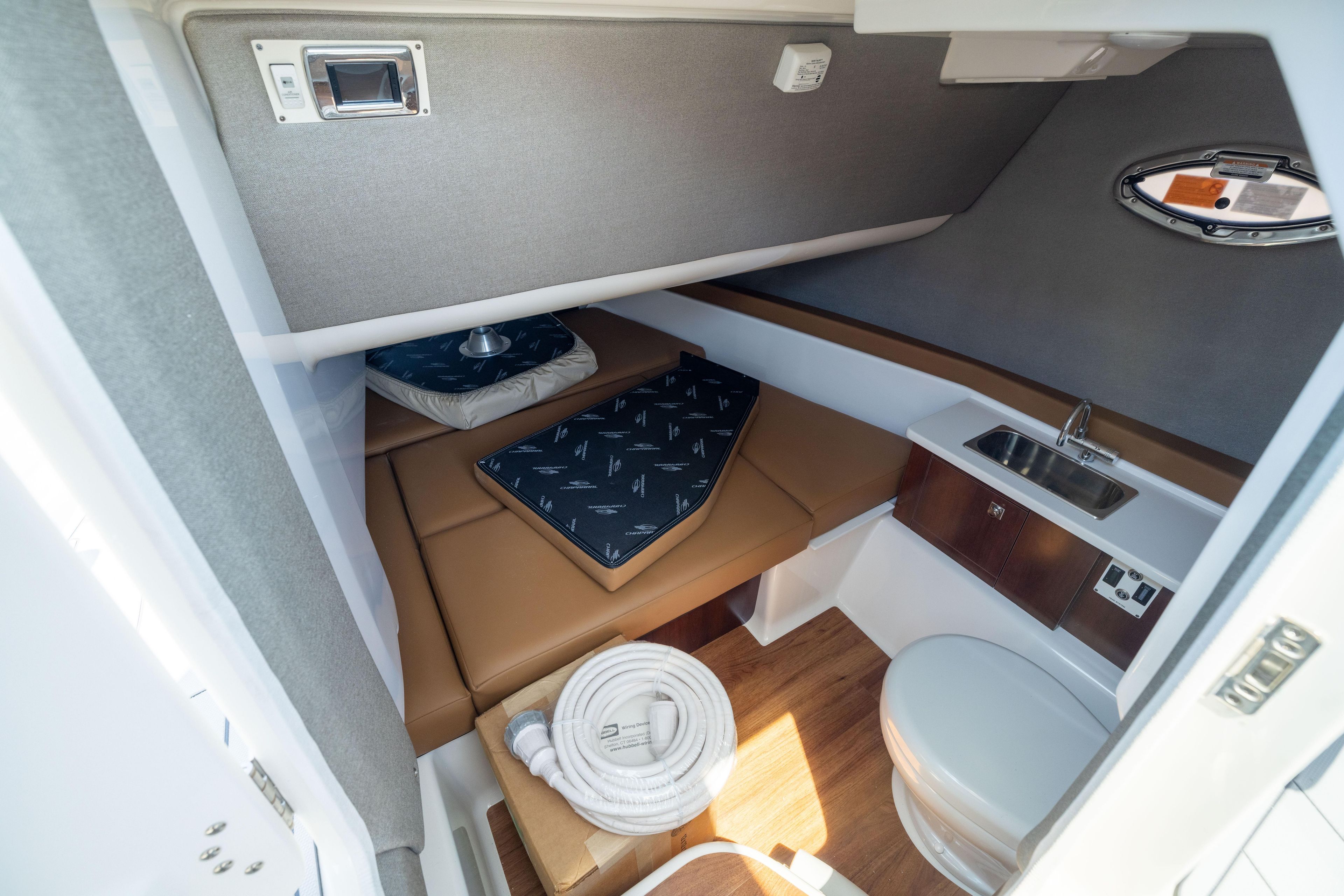 2026 Chaparral 310 OSX cabin interior with bed, sink, and toilet.