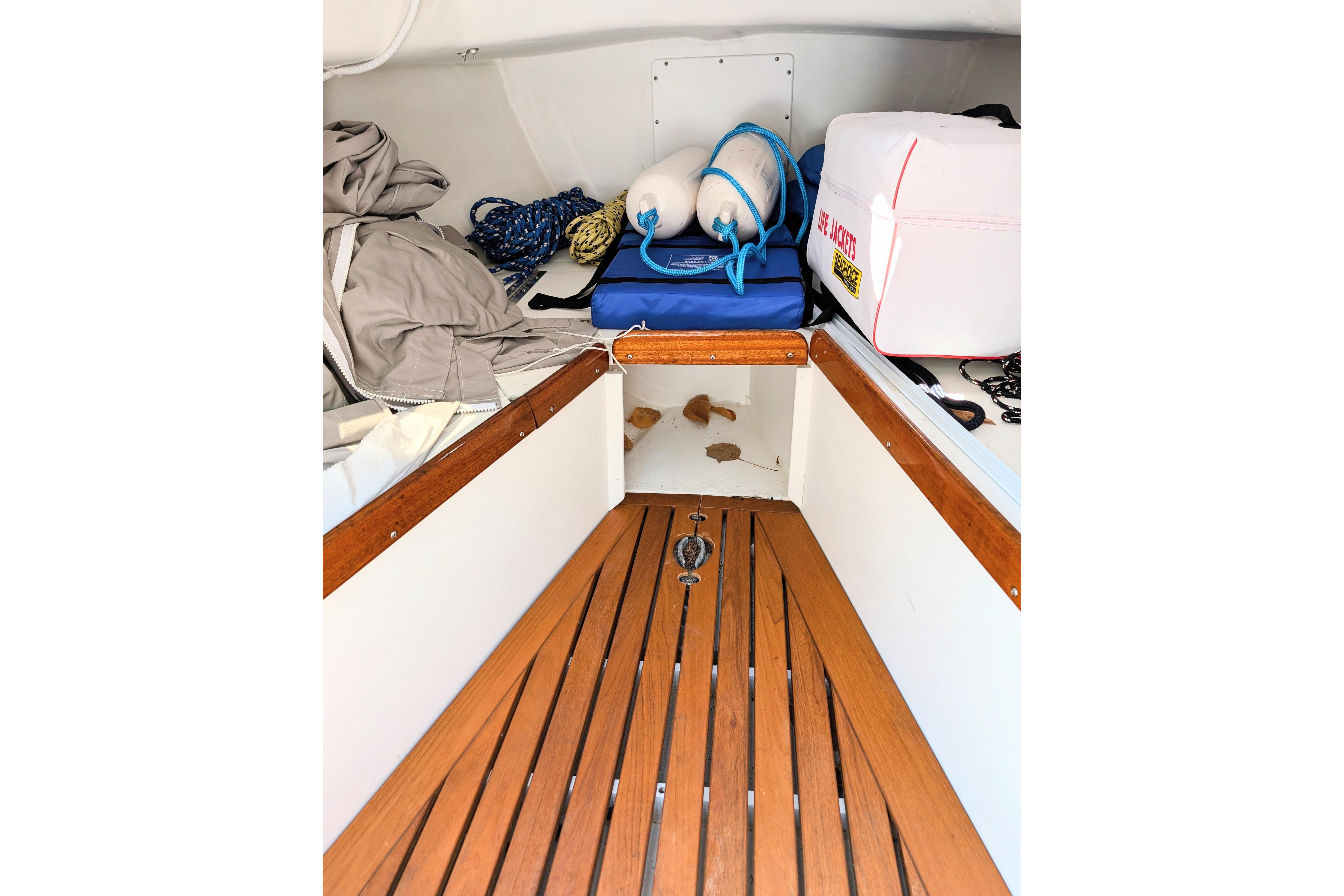 Interior of a 1965 Pearson Ensign sailboat with wooden flooring and nautical gear.