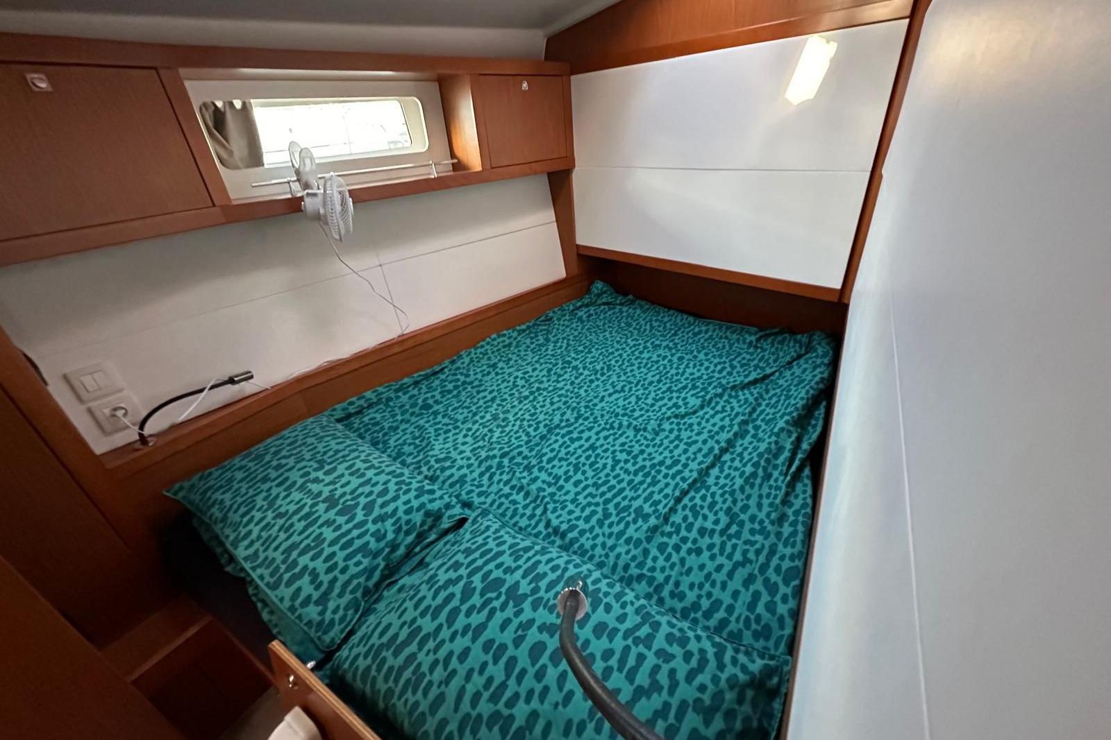 Cozy cabin interior of 2013 Beneteau Sense 50 yacht with teal bedding.