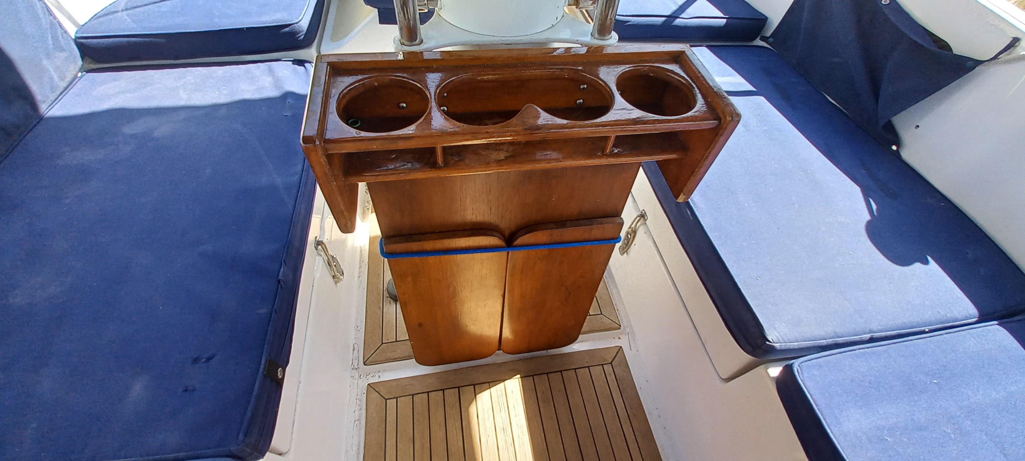 Interior of 1998 Nonsuch 33 sailboat with wooden table and blue cushioned seating.