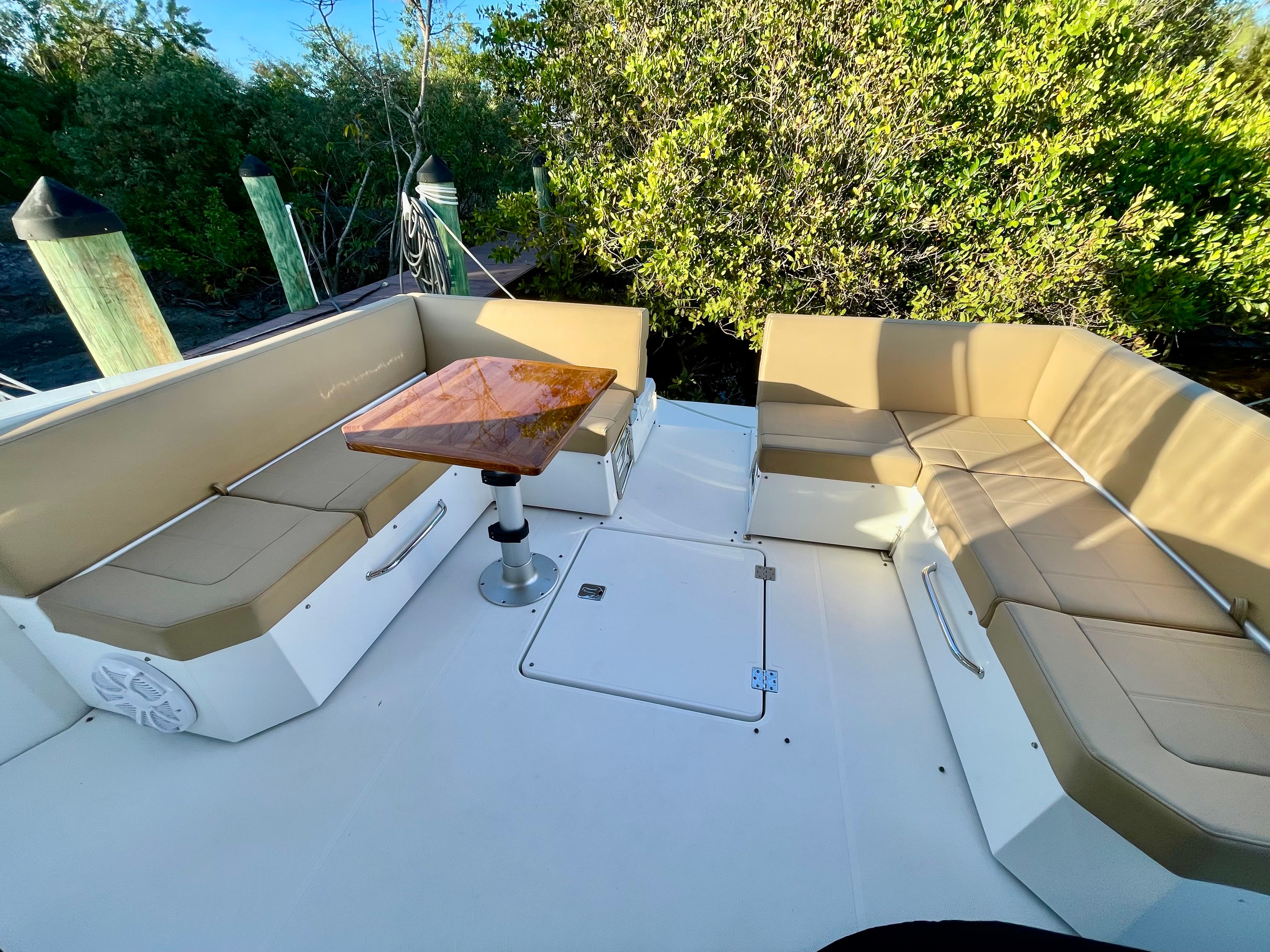 The image shows the seating area of a 2016 Cruisers Yachts 390 Express Coupe with a wooden table.