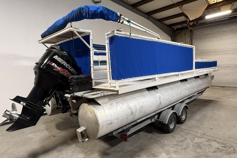 1993 Monark Sun Caster 240 CR 4 Point pontoon boat with Mercury engine in a warehouse.
