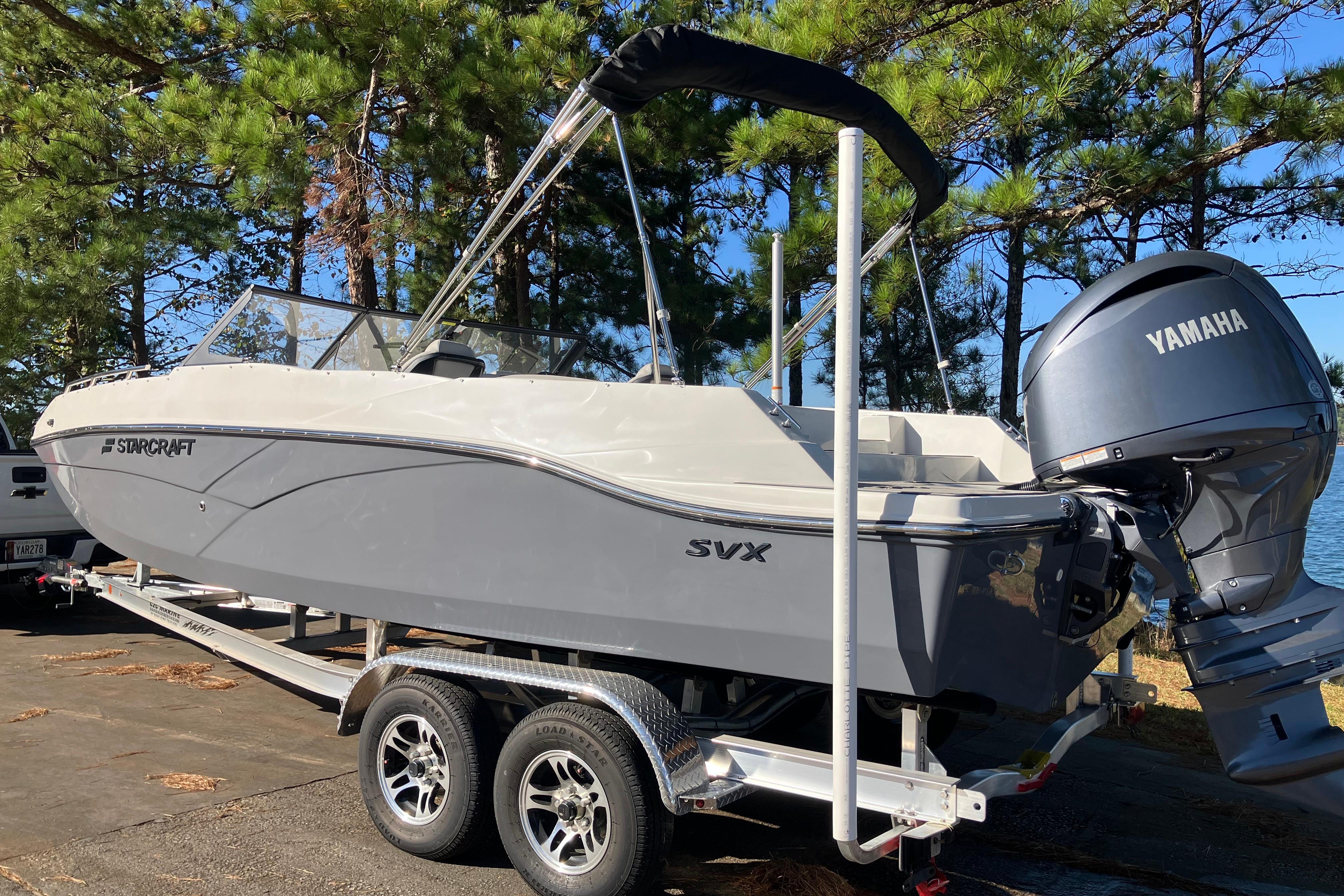 2025 Starcraft SVX 210 OB boat on trailer with Yamaha outboard motor, surrounded by trees.