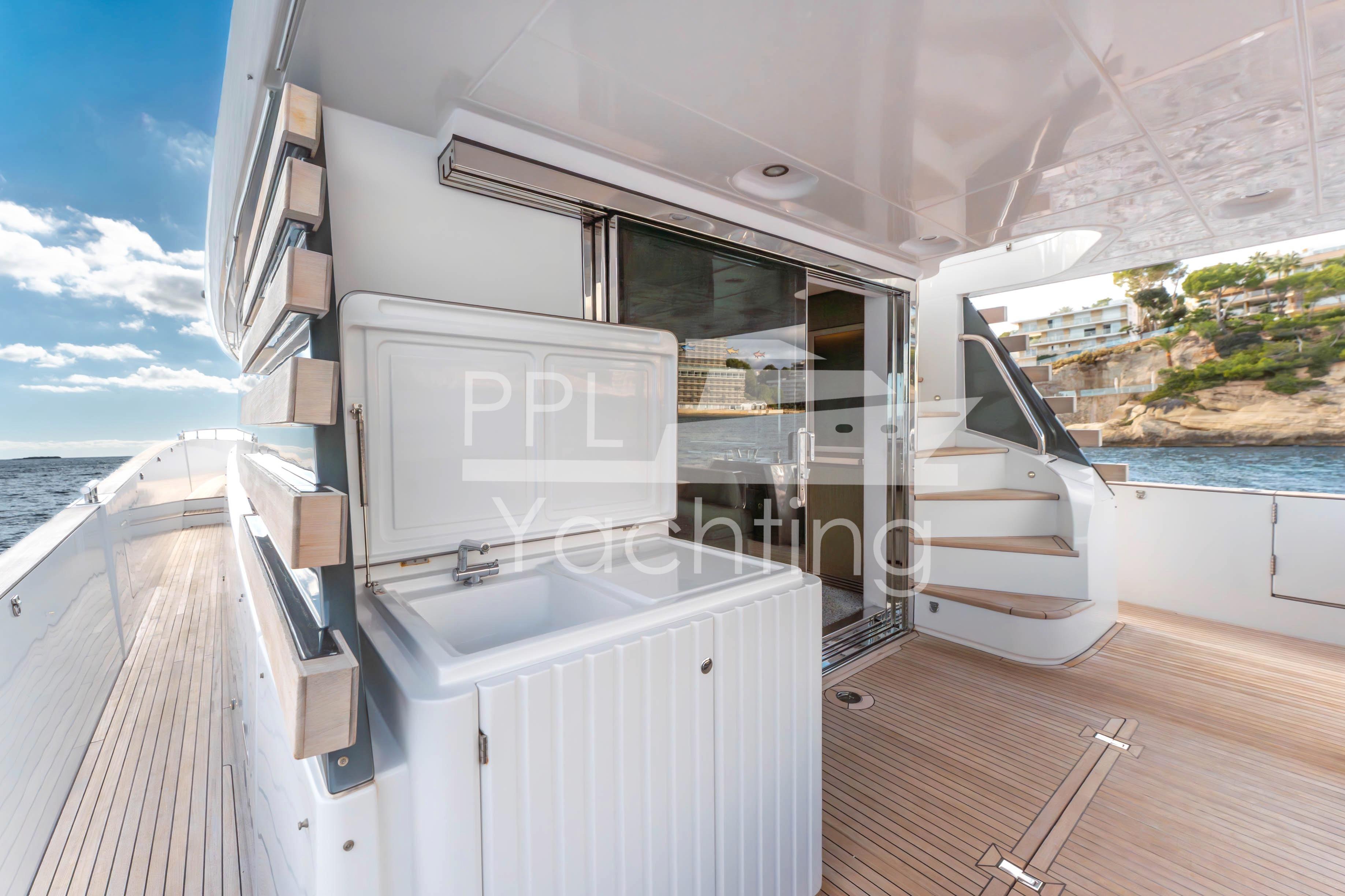 Azimut Magellano 66 yacht deck with open sliding doors, ocean view, and sunny sky.