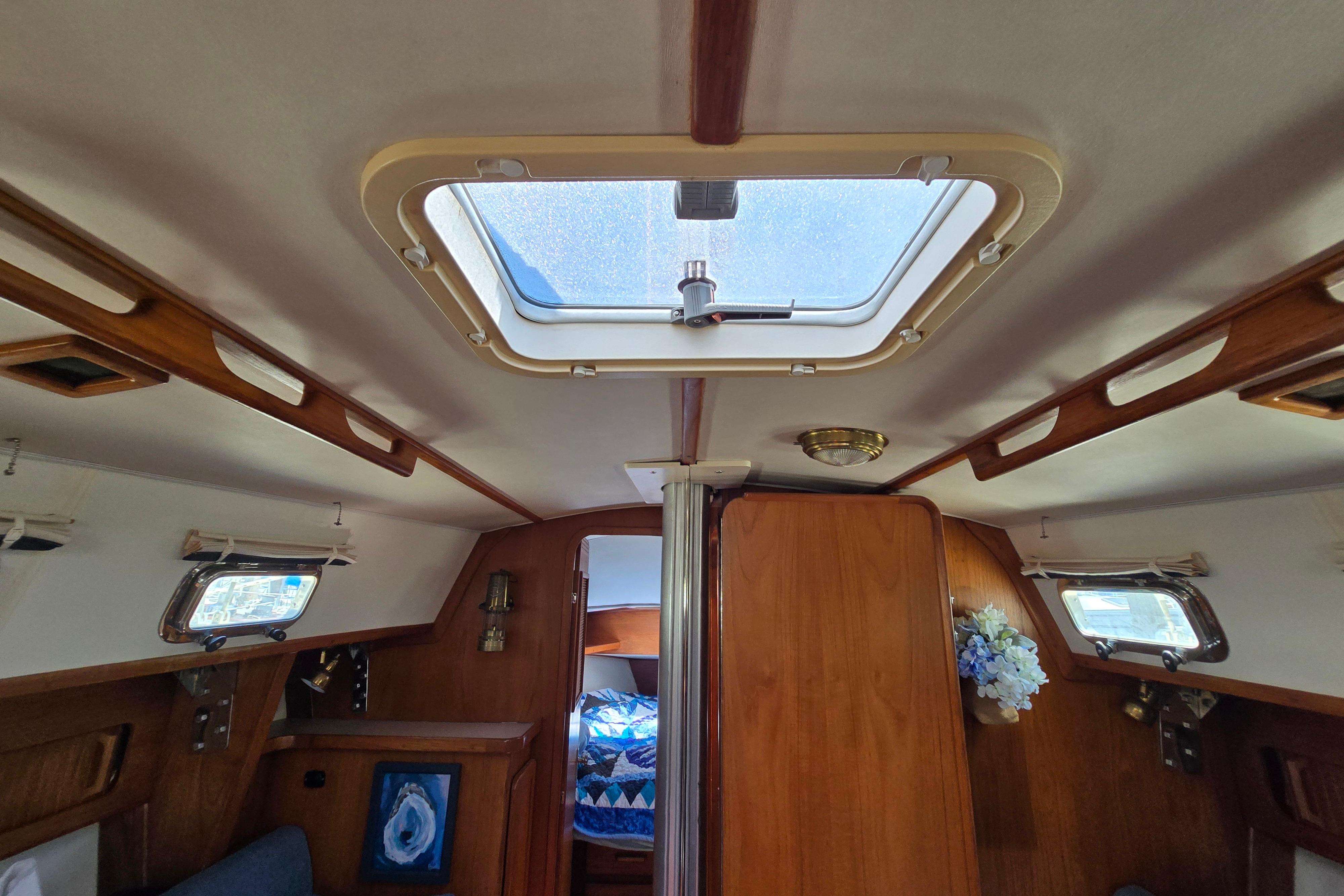 Interior of a 1993 Caliber 35 sailboat, featuring wooden accents and a skylight.