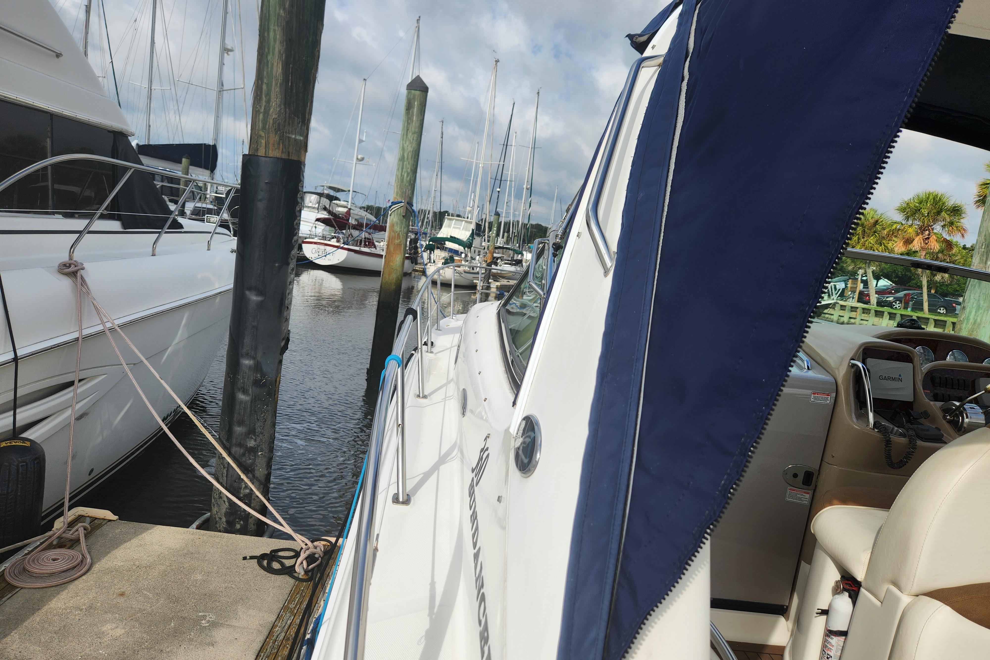2003 Sea Ray 360 Sundancer docked at marina with blue canopy and visible cockpit.