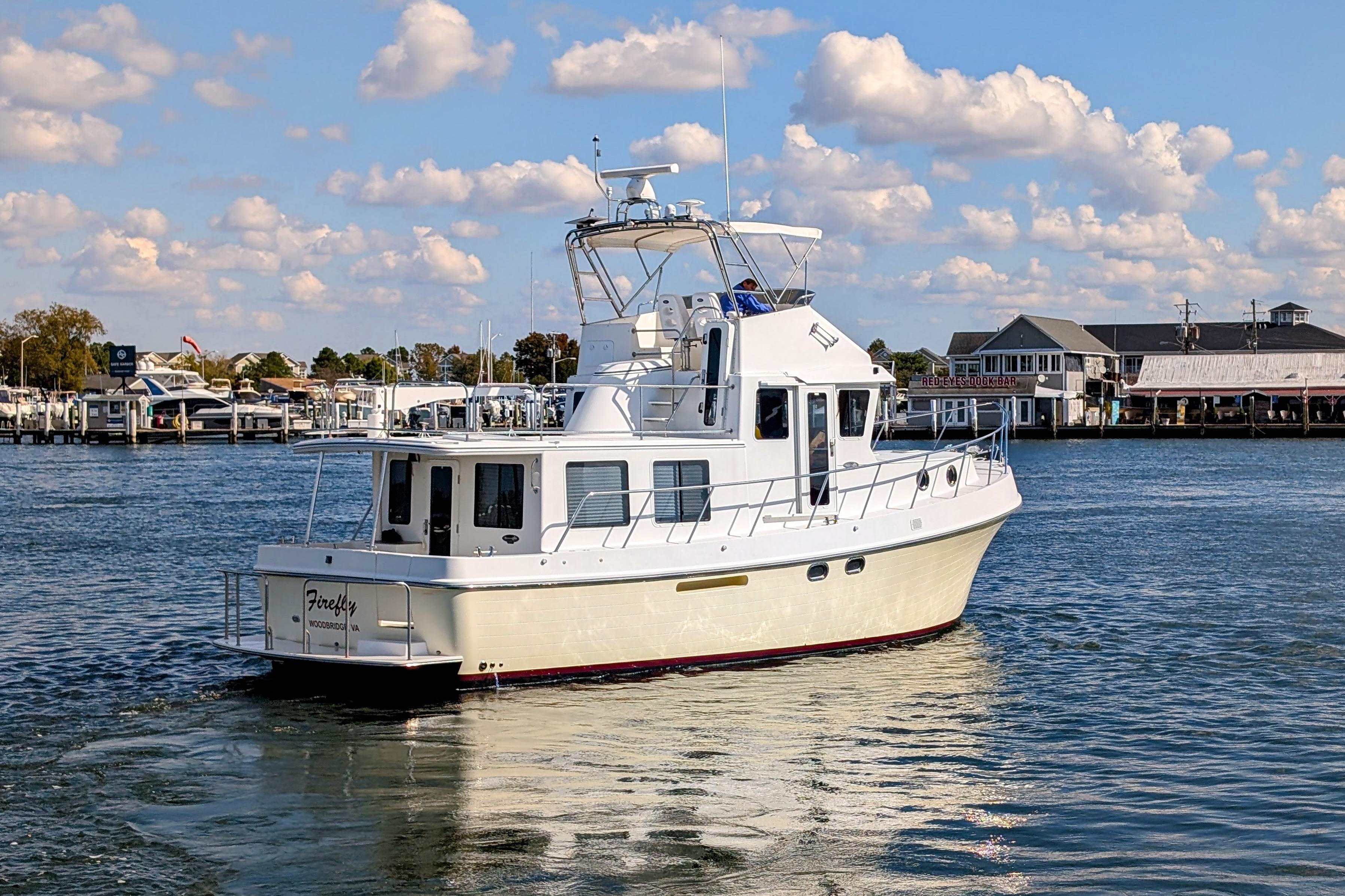 2015 American Tug 435 cruising in a scenic marina under a partly cloudy sky.