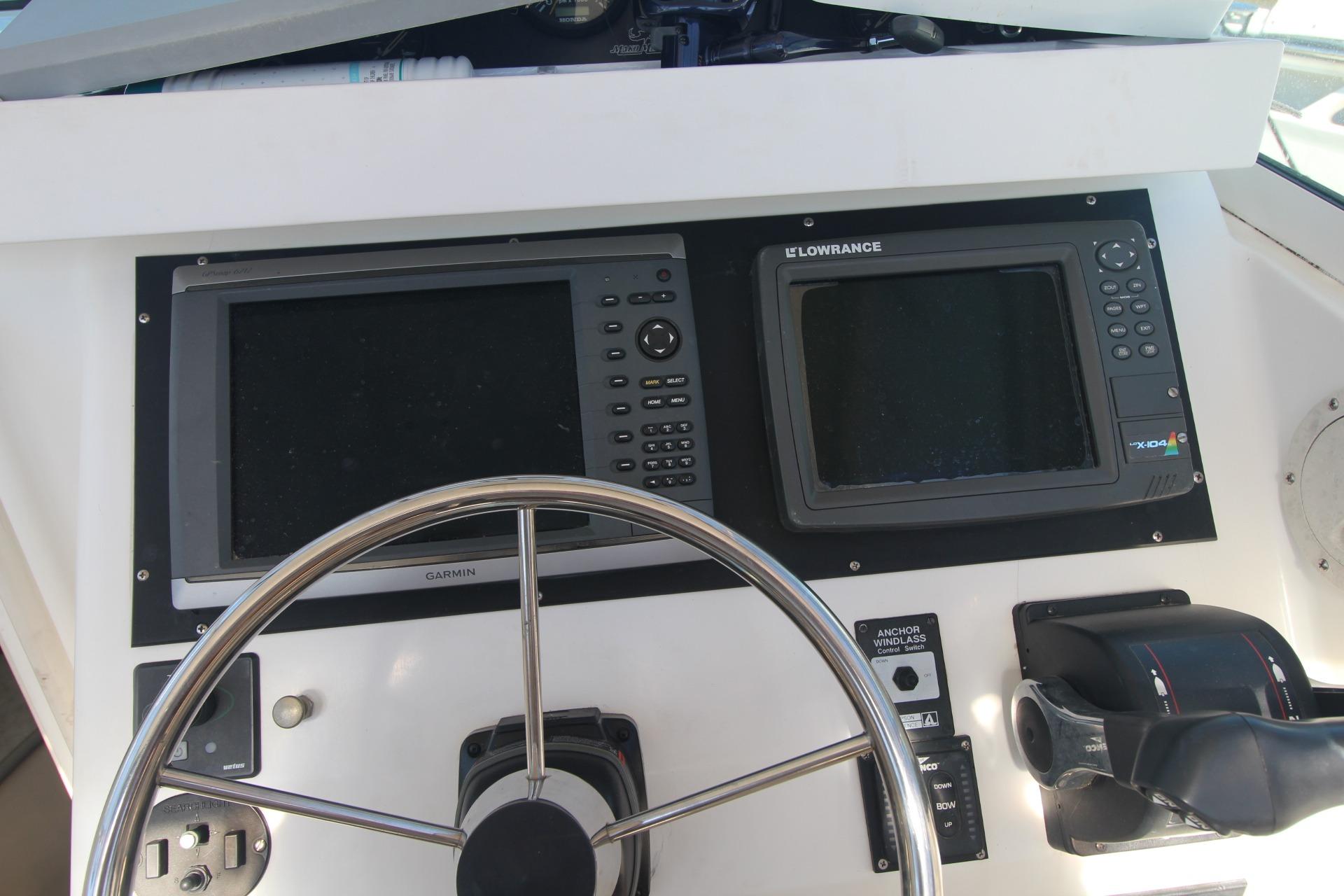 Boat dashboard of a 2001 Mako 293 Walk Around with Garmin and Lowrance displays.