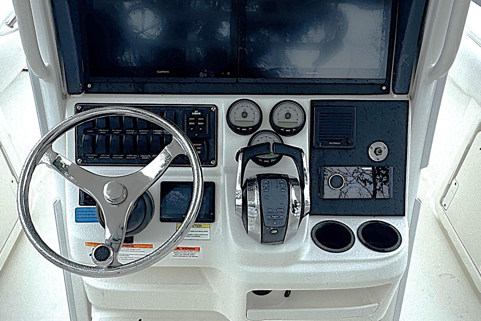 Control panel of a 2014 Boston Whaler 250 Outrage boat with steering wheel and gauges.