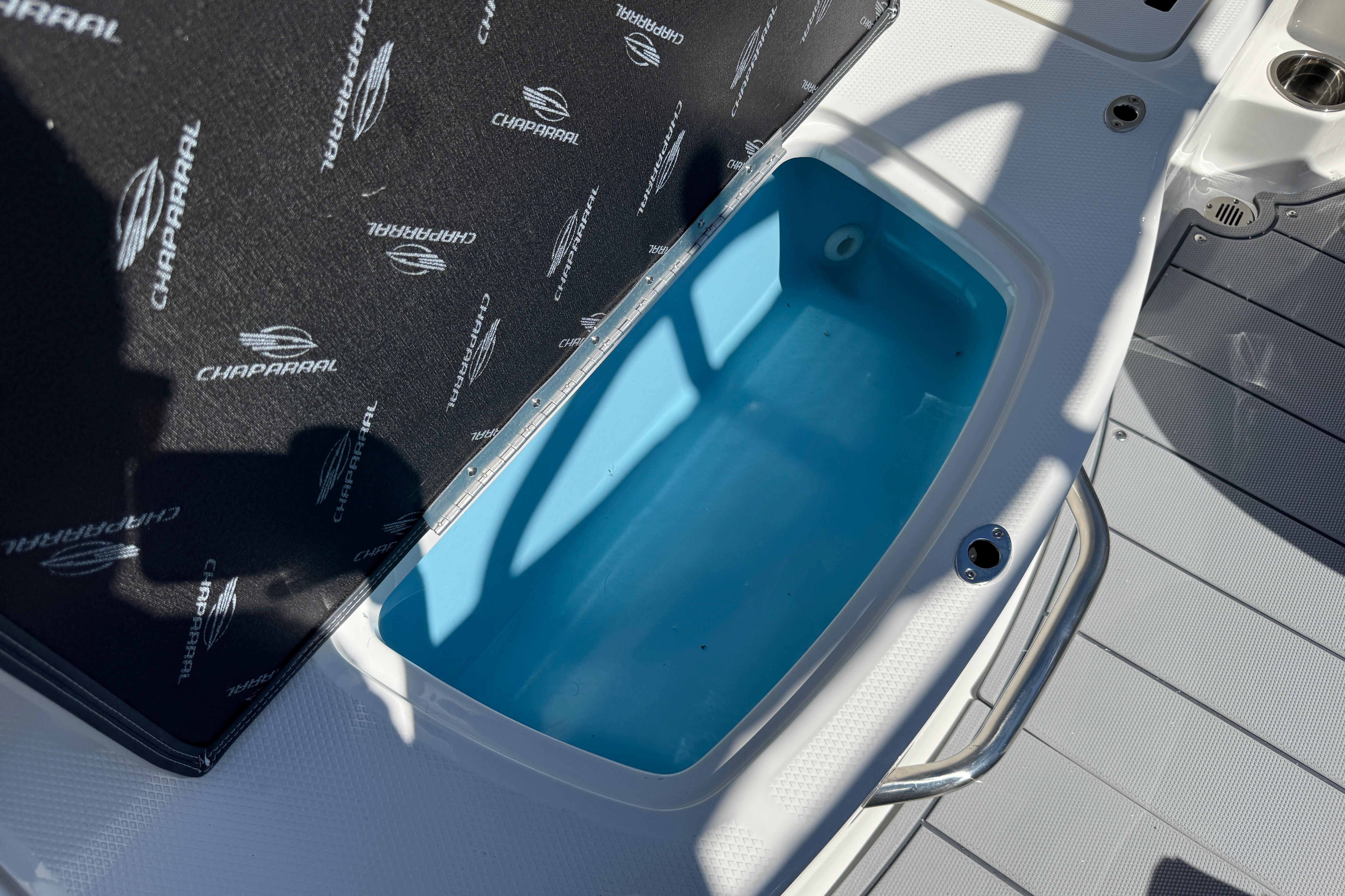 2026 Chaparral 21 SSi boat storage compartment with branded cover and blue interior.