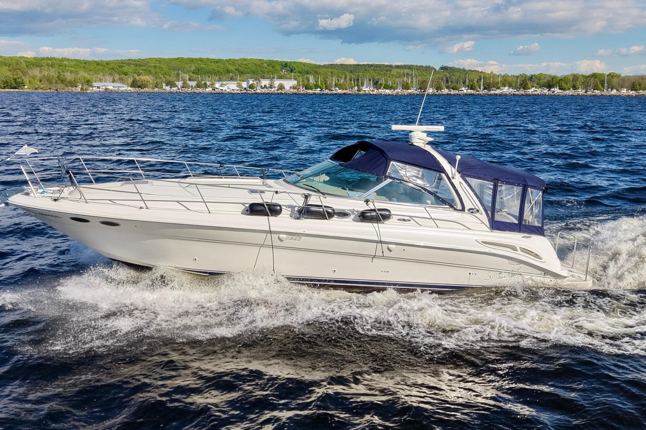 2002 Sea Ray 410 Sundancer cruising on a sunny day with blue skies and water.
