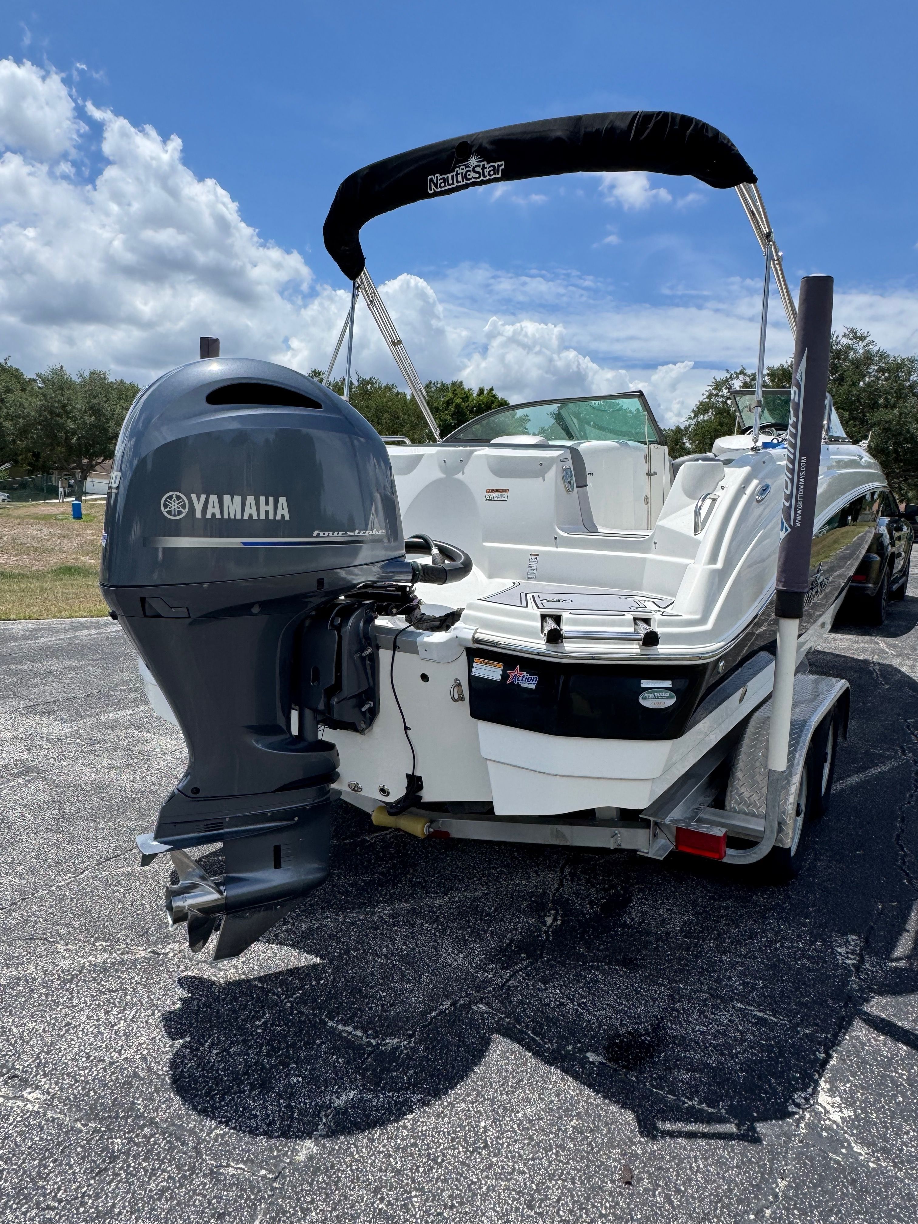 A white boat with a Yamaha outboard motor sits on a trailer under a blue sky.