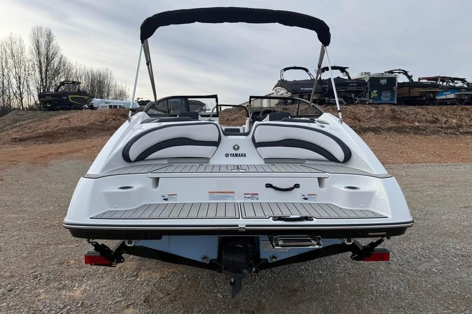 2026 Yamaha Boats SX195, rear view, on a gravel surface with other boats in background.